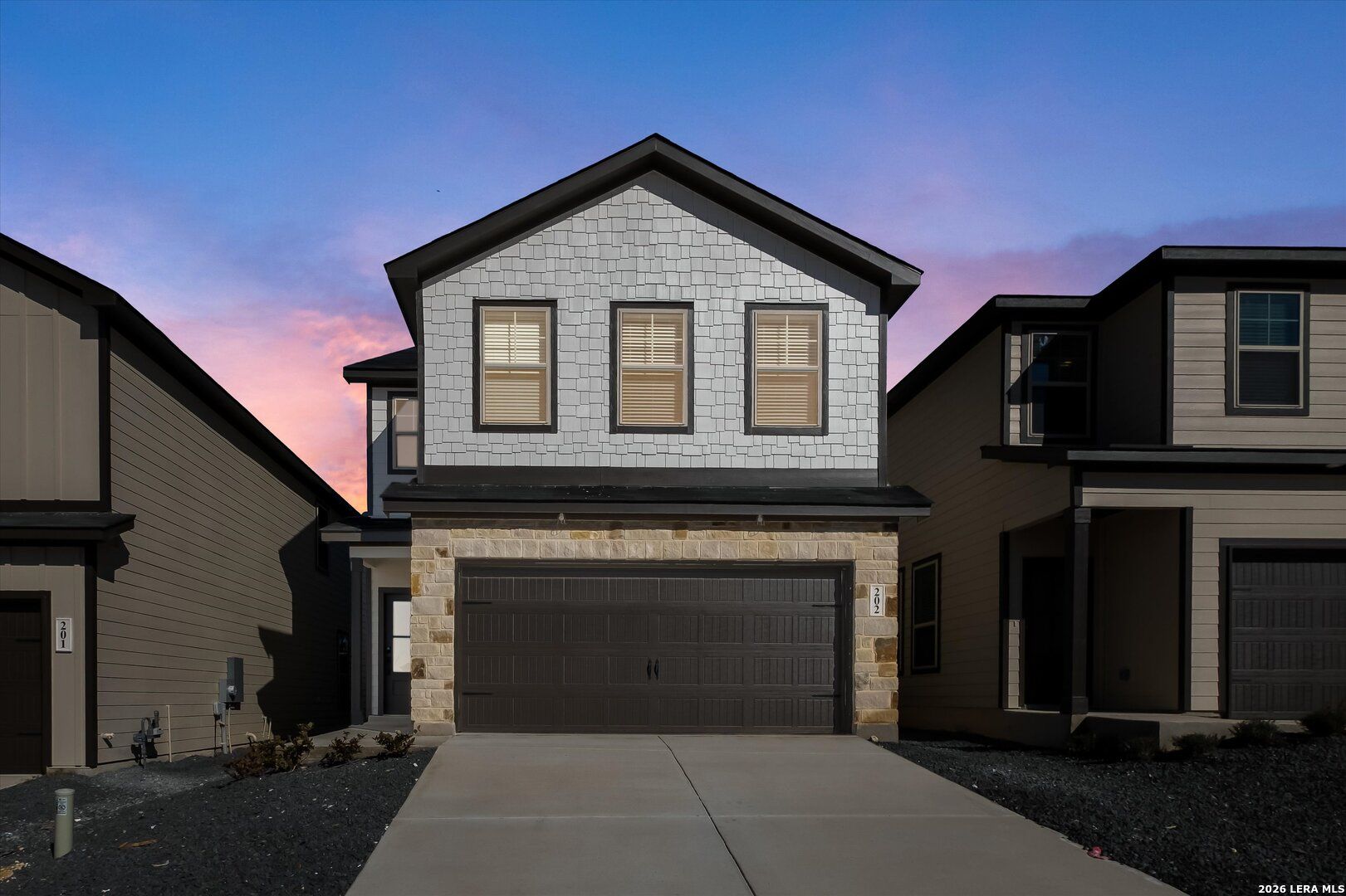 Modern 2-story Gillian B home exterior with stone accents, 2-car garage, driveway under sunset sky in San Antonio, TX