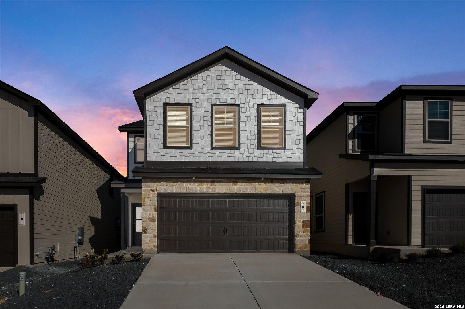 Modern 2-story Gillian B home exterior with stone accents, 2-car garage, driveway under sunset sky in San Antonio, TX