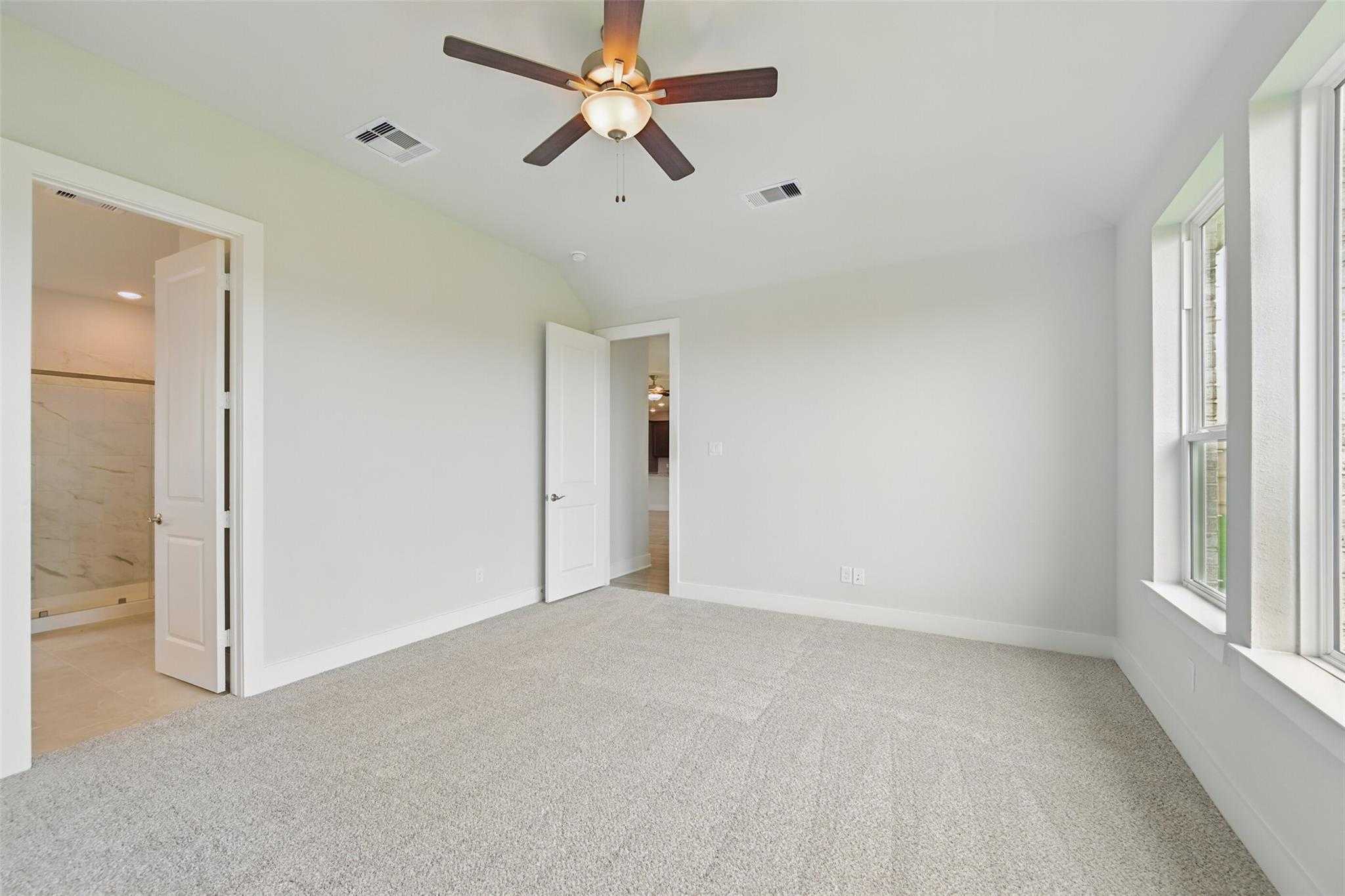 Spacious secondary bedroom with dual ceiling fans, carpet floors, and bathroom access in Davidson Homes The Philip A, Lago Mar, Texas City