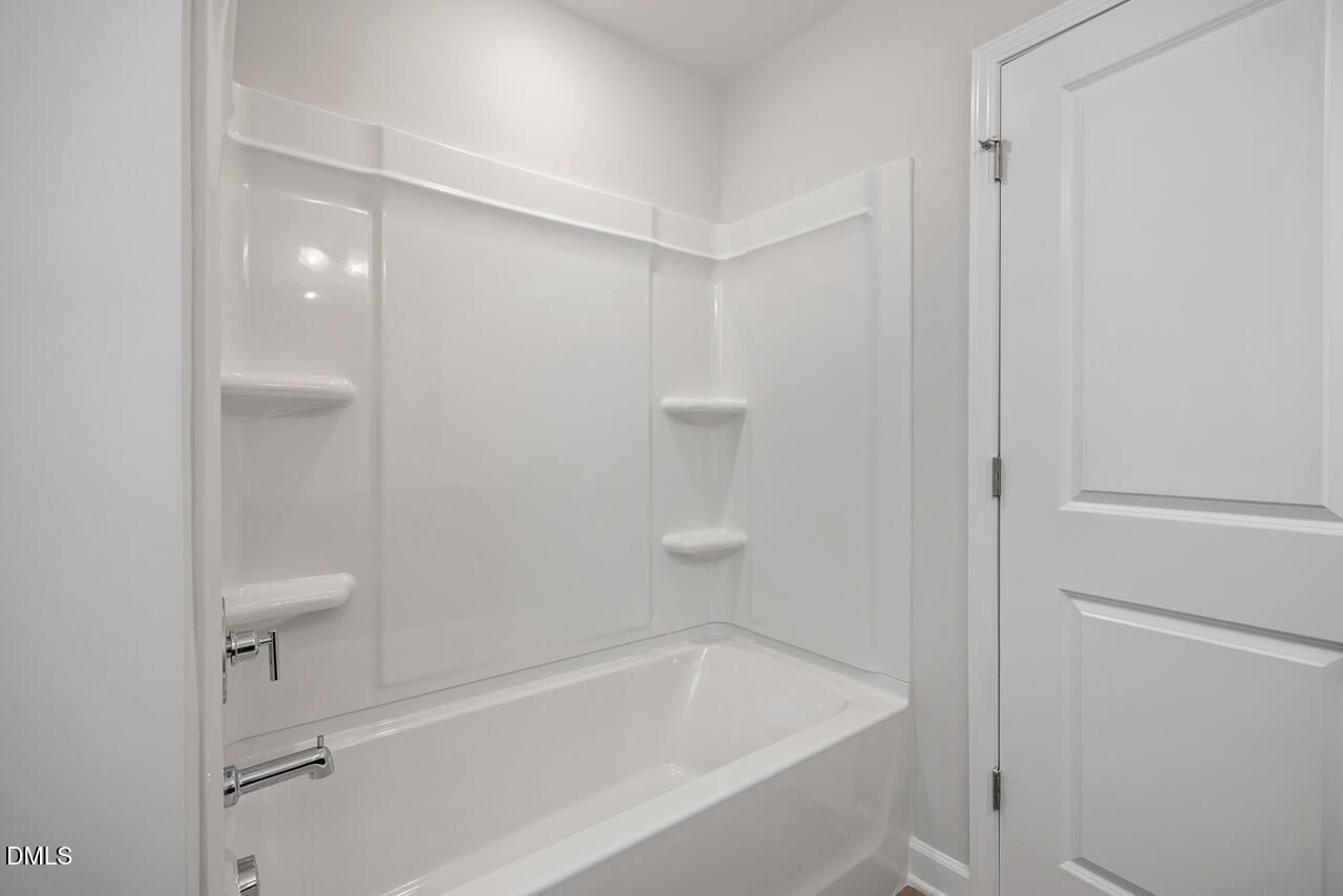 Modern bathroom with white tub and shower surround in The Adalynn A floor plan at Gregory Village, Lillington, NC.