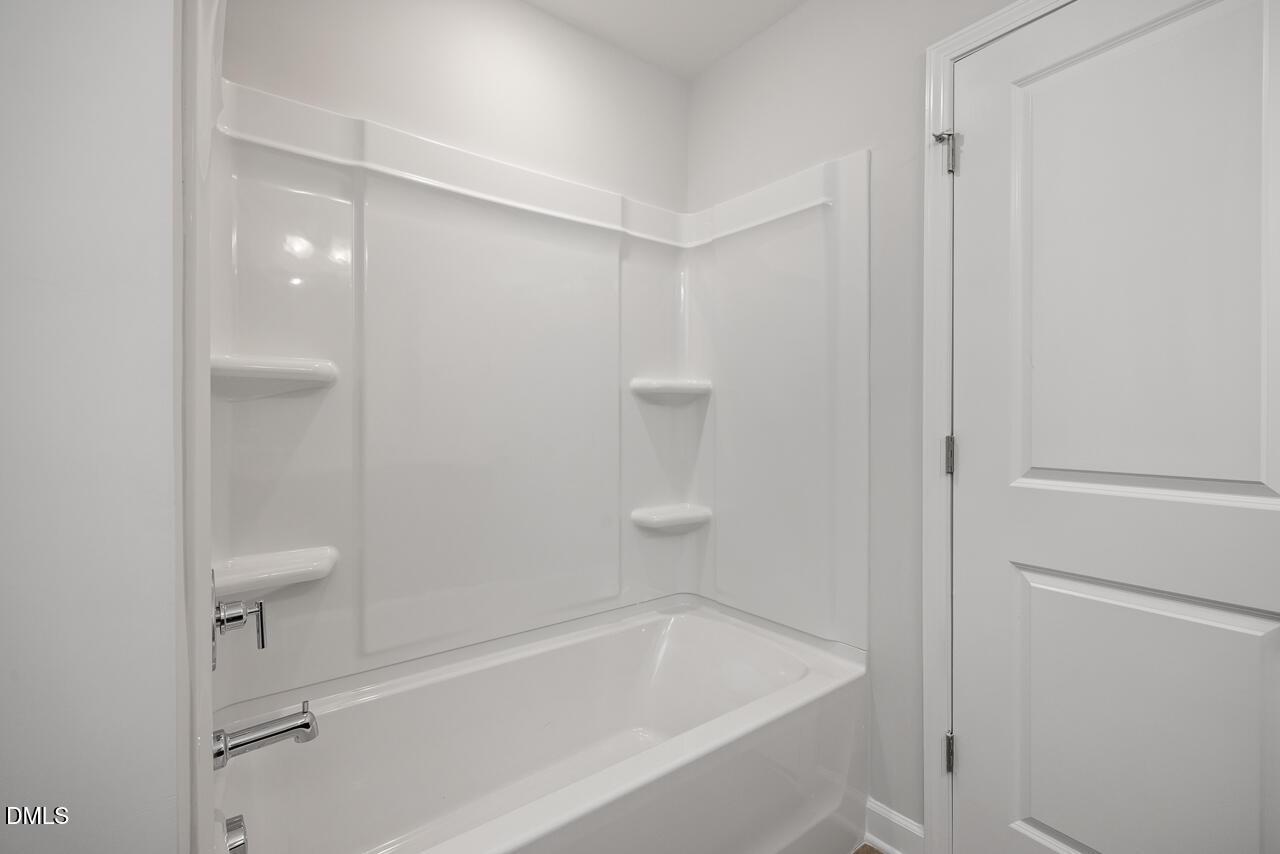Modern bathroom with white tub and shower surround in The Adalynn A floor plan at Gregory Village, Lillington, NC.