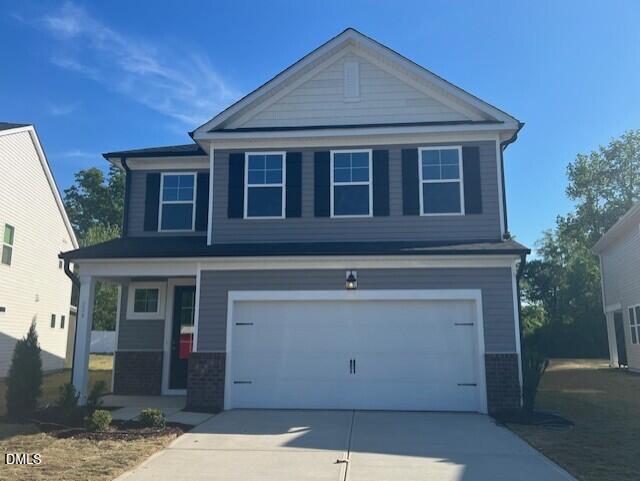 Two-story gray home with white garage, black shutters, brick accents, and front porch in Gregory Village, Lillington, NC - Davidson Homes Preston A
