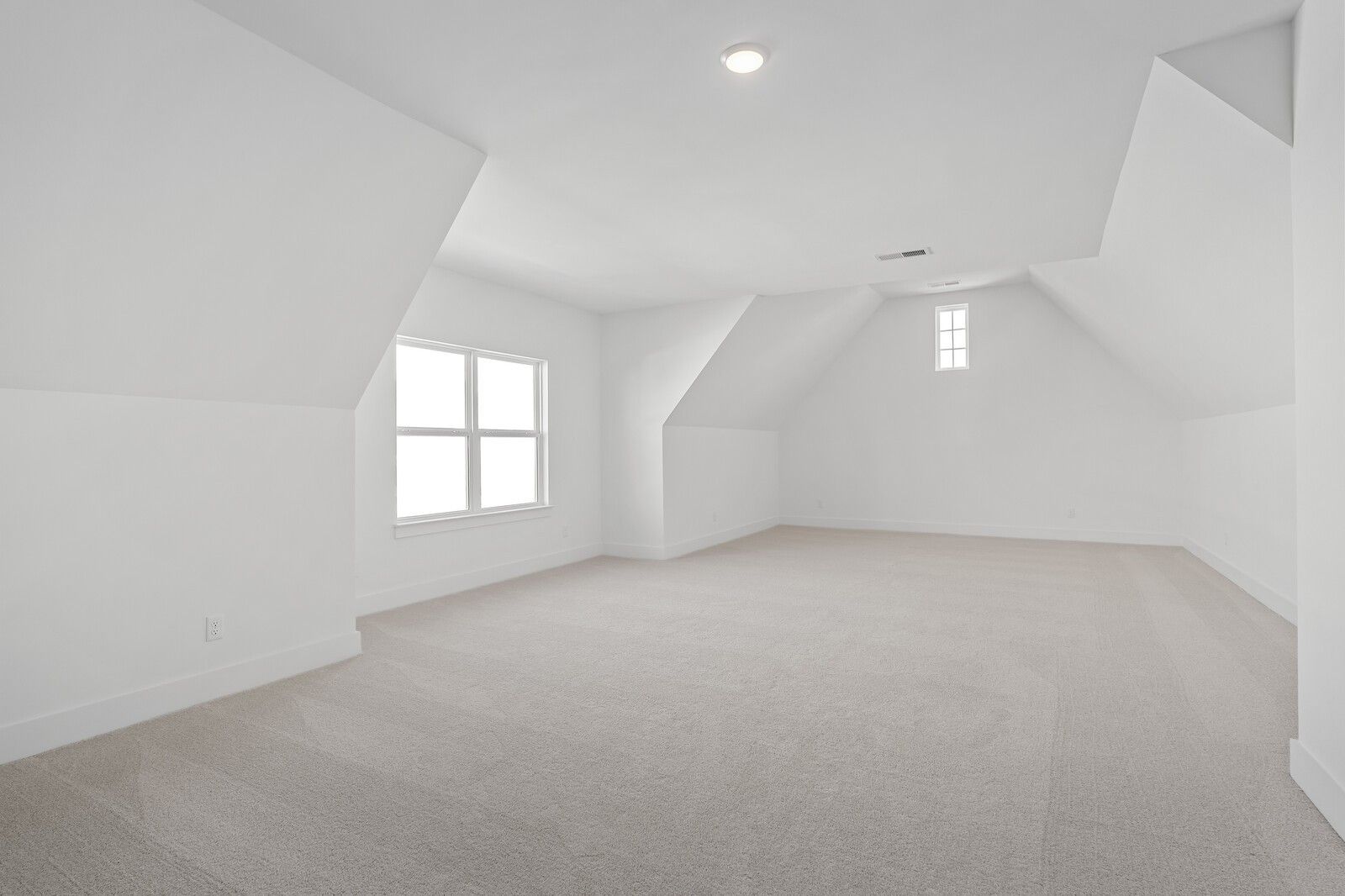 Bright empty bedroom with vaulted ceilings, dormer windows, and beige carpet in Davidson Homes The Hawkins, Murfreesboro, TN