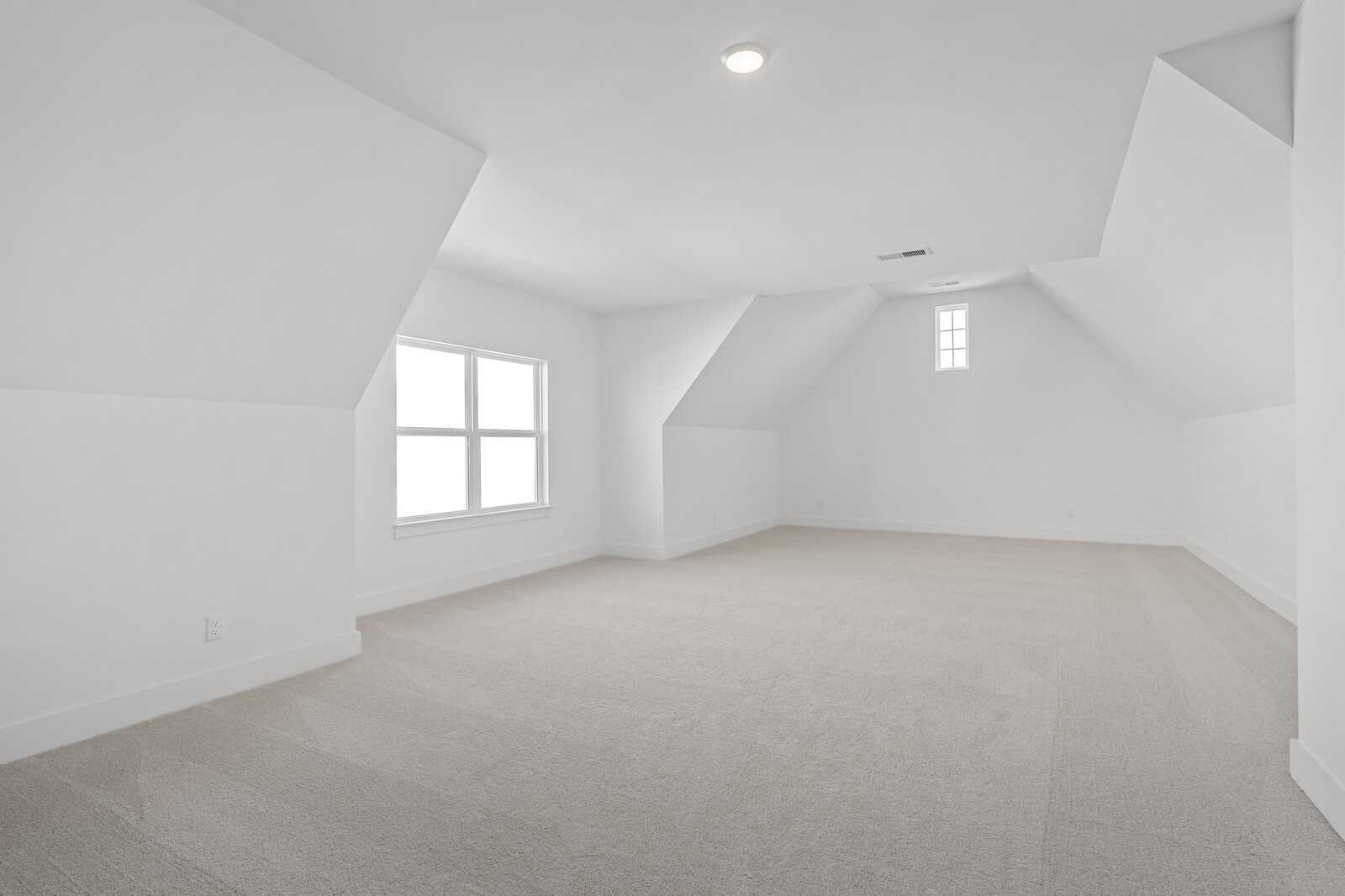 Bright empty bedroom with vaulted ceilings, dormer windows, and beige carpet in Davidson Homes The Hawkins, Murfreesboro, TN