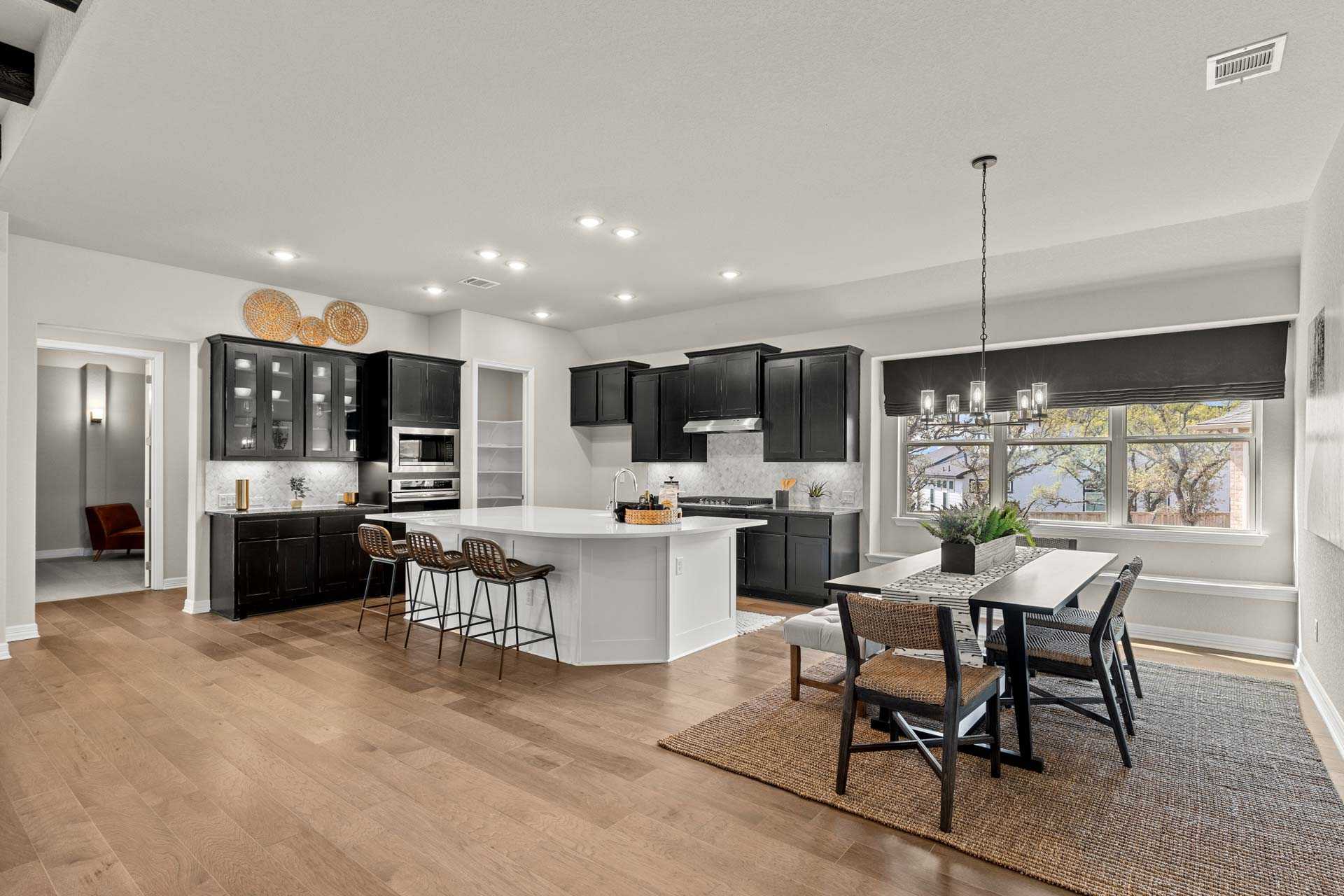 Spacious gourmet kitchen in The Summerlin B featuring black cabinets, white island, bar stools, and open dining area