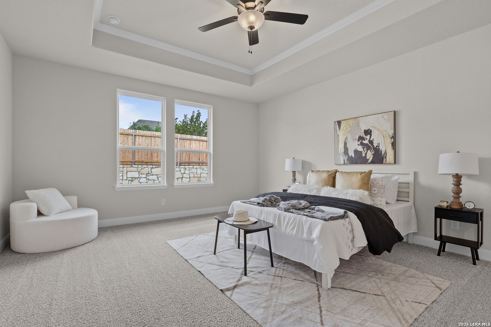 Serene master bedroom with white upholstered bed, gray walls, large windows to backyard, ceiling fan in Davidson Homes The Lanier G, Castroville, TX