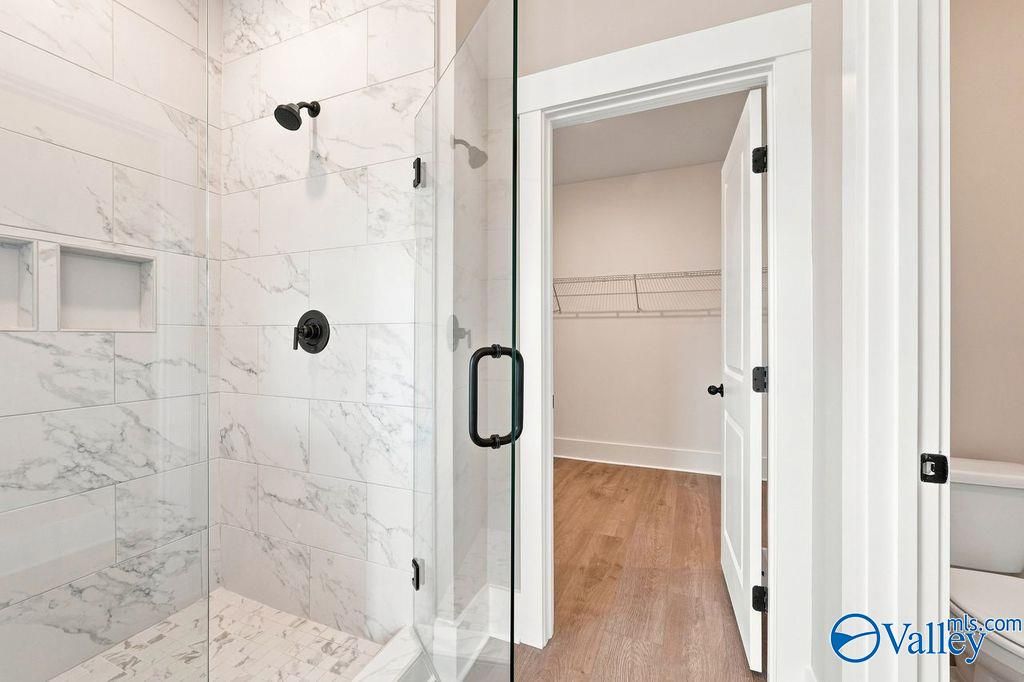 Walk-in shower with marble-style tile and walk-in closet in The Rockford floor plan by Davidson Homes in Hartselle, Alabama.