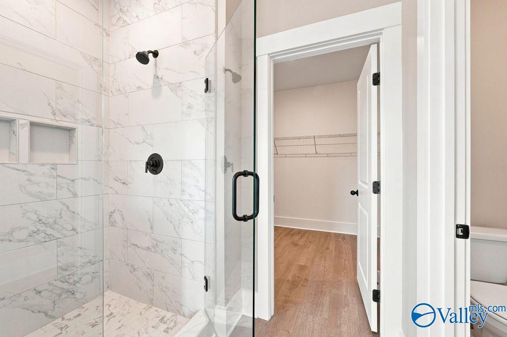 Walk-in shower with marble-style tile and walk-in closet in The Rockford floor plan by Davidson Homes in Hartselle, Alabama.
