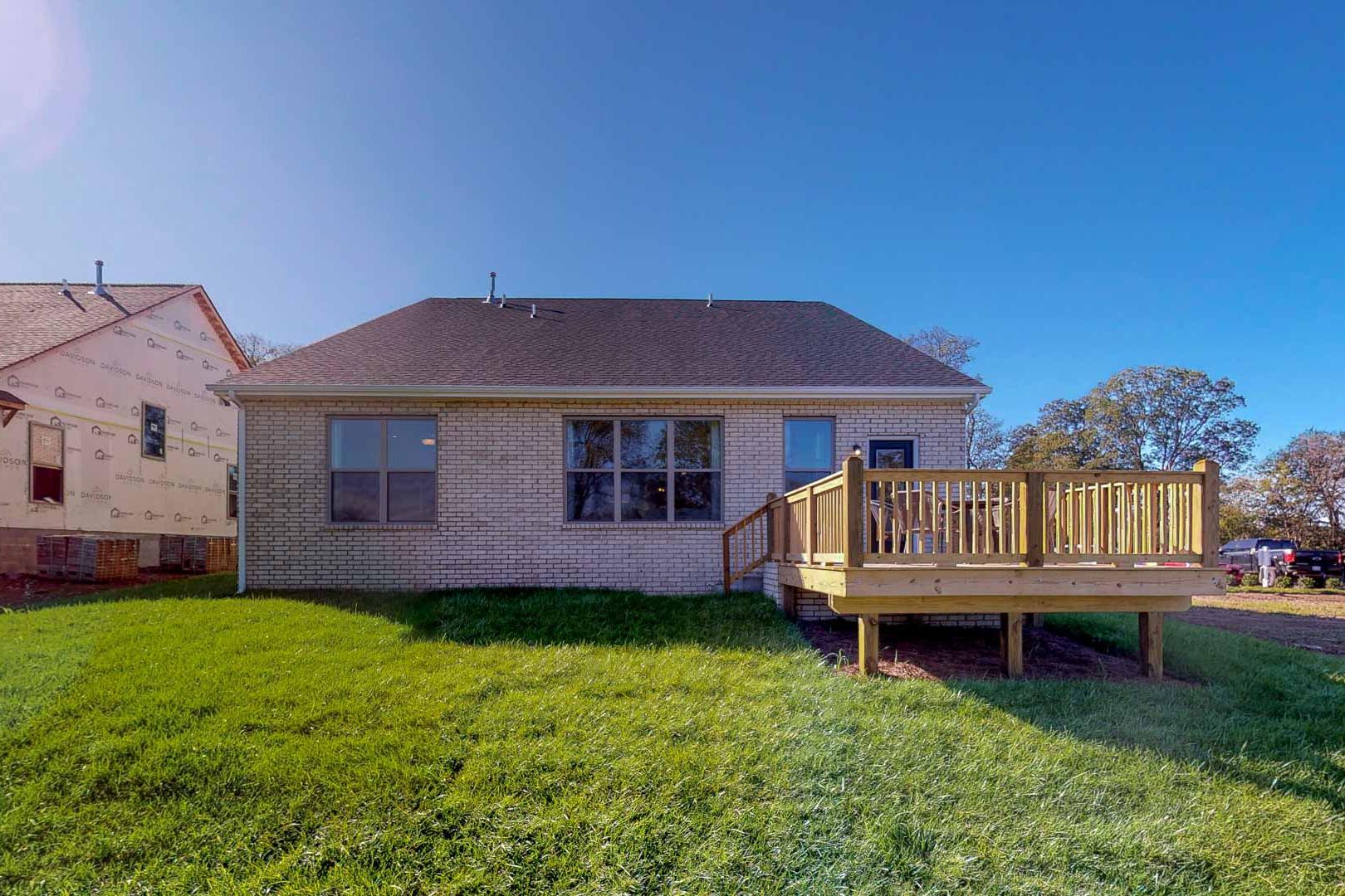 Rear brick home at Liberty Creek in Gallatin Tennessee with elevated wooden deck, large windows, and green lawn