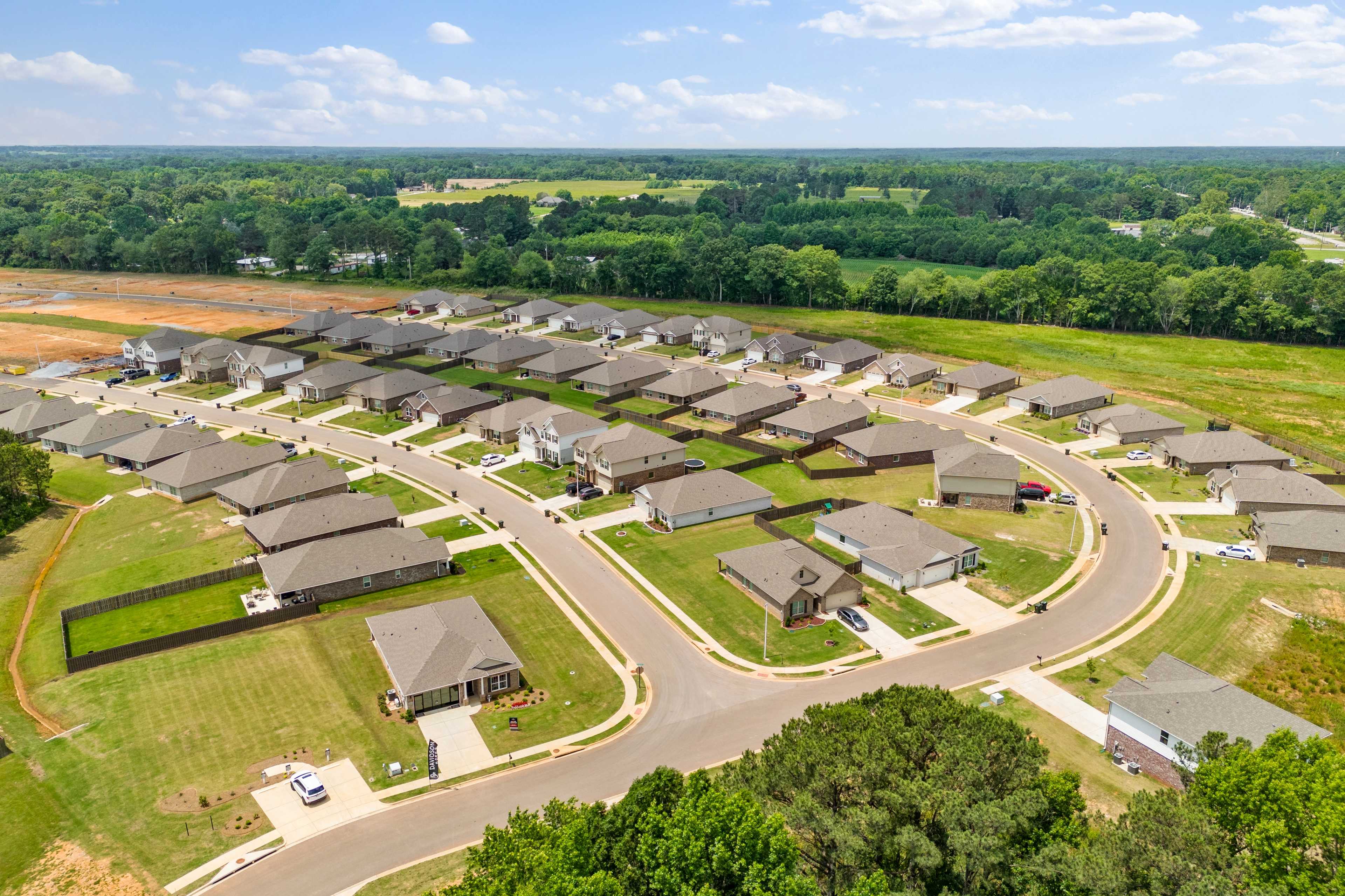 Aerial view of new Davidson Homes in Durham Farms, Harvest Alabama, with clustered houses, winding streets and wooded surroundings