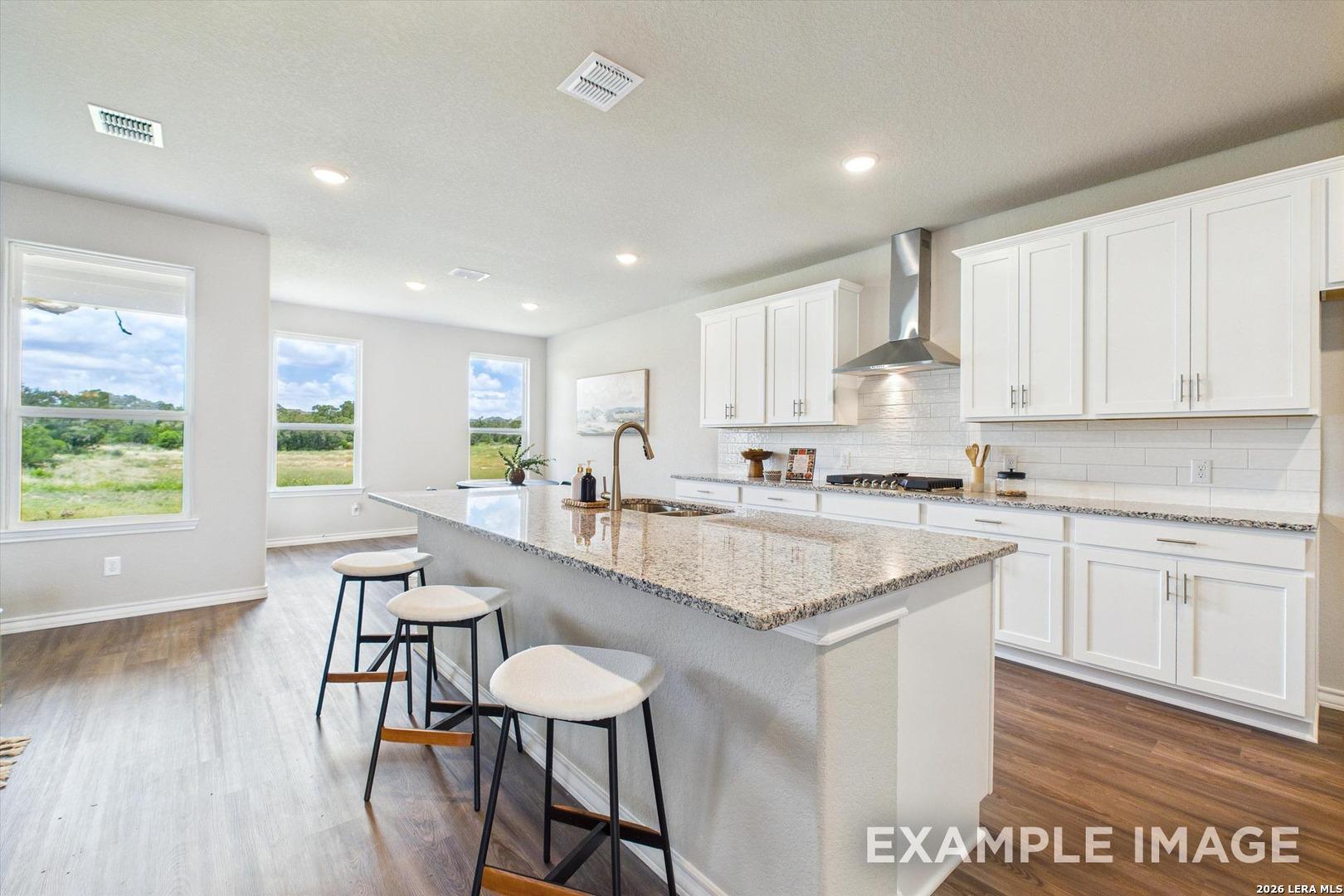 Modern kitchen with granite island and white cabinets in The Foster F floor plan at Potranco Oaks, Castroville, Texas.