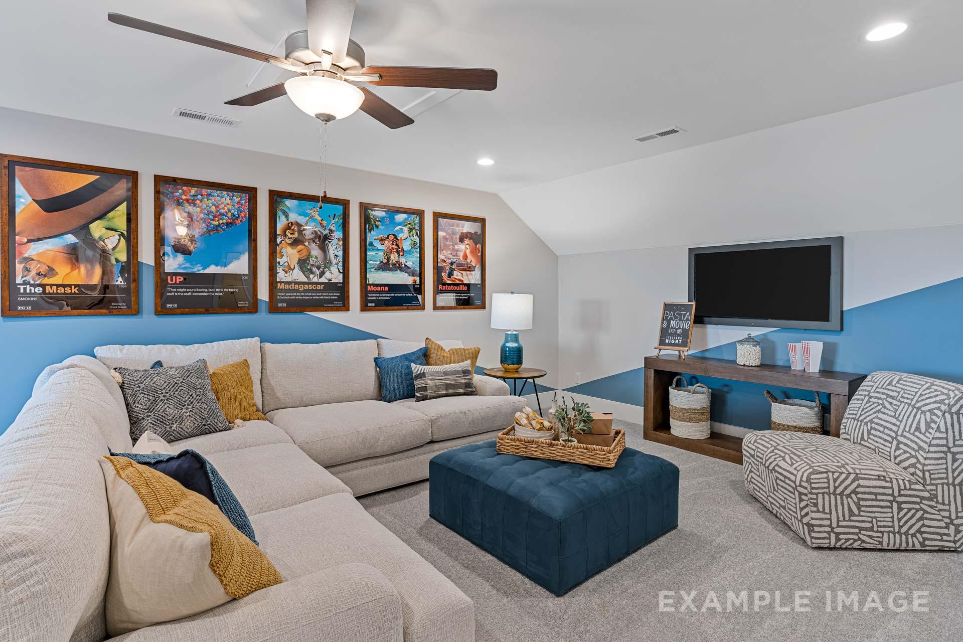 Cozy bonus room loft in The Rockford Davidson Homes design featuring L-shaped beige sofa, blue accents, wall TV, movie posters, and ceiling fan