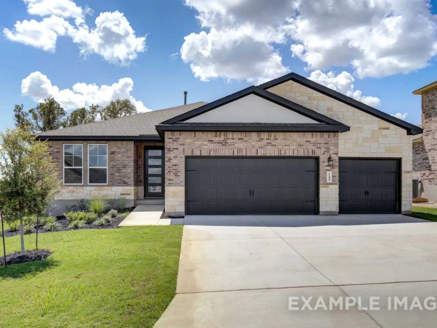 Modern 1-story brick home with black 2-car garage, landscaped yard, and blue skies in The Reserve at Potranco Oaks, Castroville, Texas