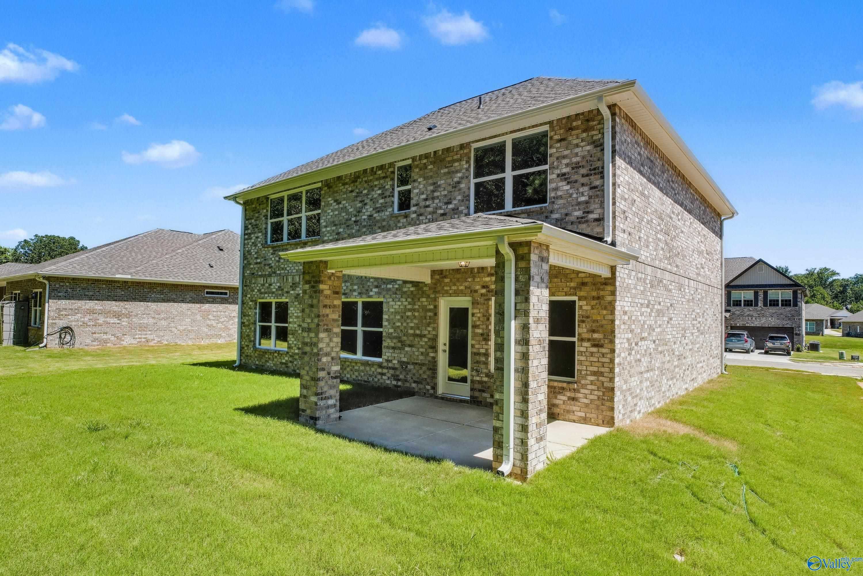 Two-story brick home with covered front porch, attached garage, and lush green lawn in The Highlands, Arab, Alabama - Davidson Homes The Shelby A
