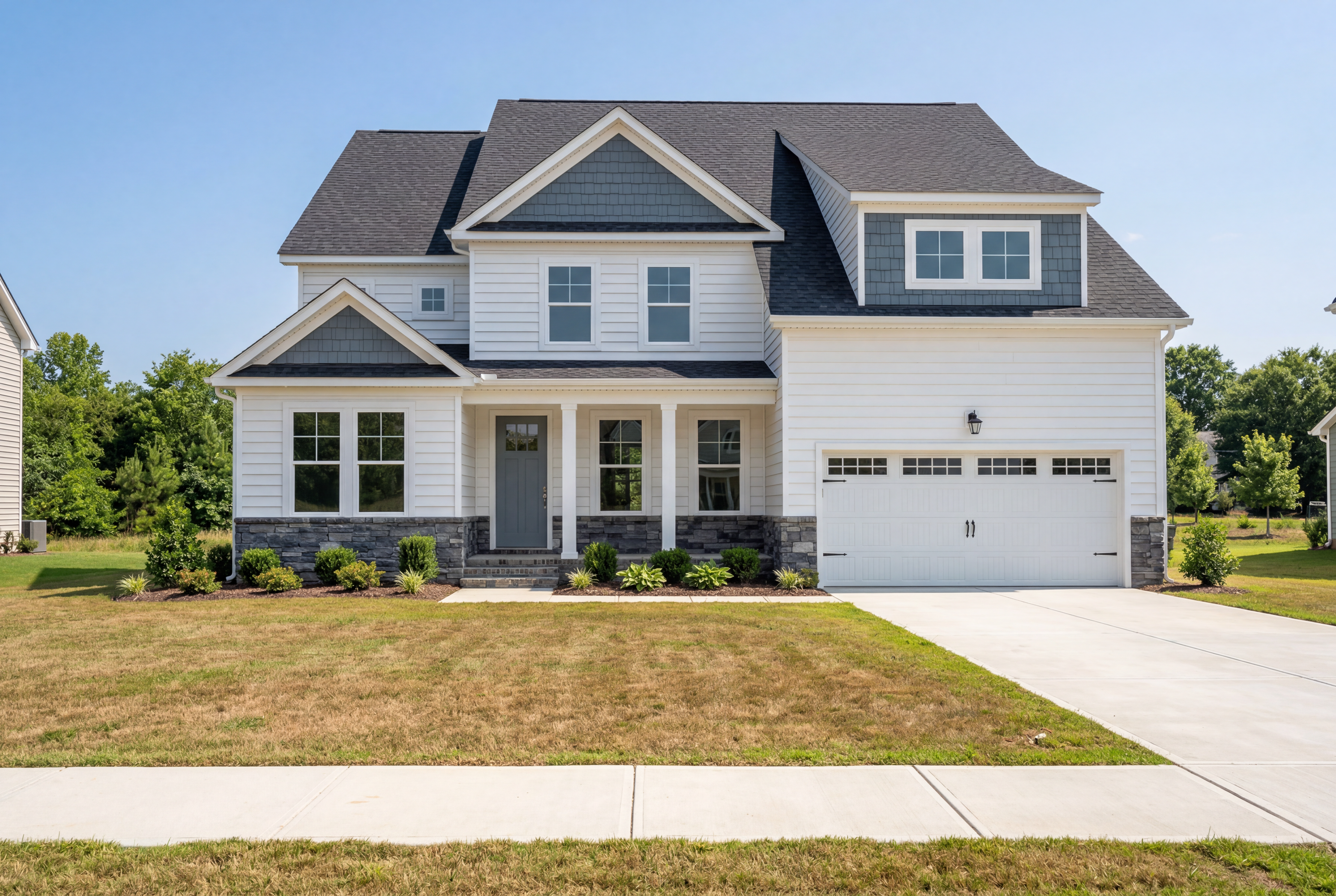 Two-story Crawford B home with stone and vinyl exterior, 2-car garage, covered porch, and dormer window in Holly Springs