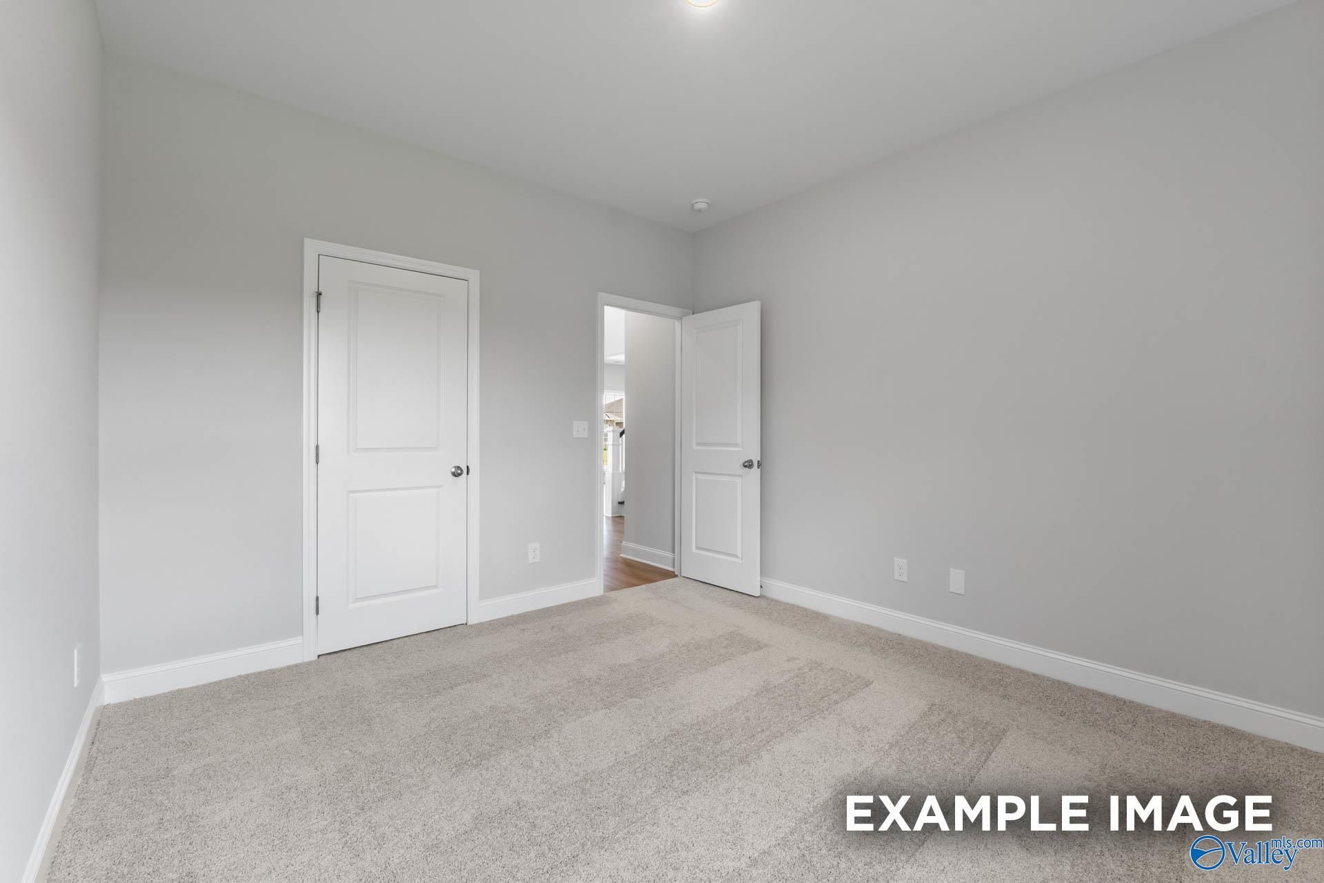 Spacious secondary bedroom with gray walls, white doors, and plush carpet in Evermore Homes The Madison D, Madison, Alabama