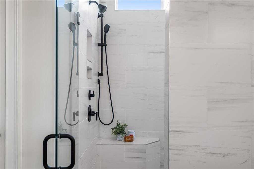 Modern frameless glass shower with rain and handheld heads, white subway tile, niche shelf in Davidson Homes Seaside B master bath, Woodstock GA