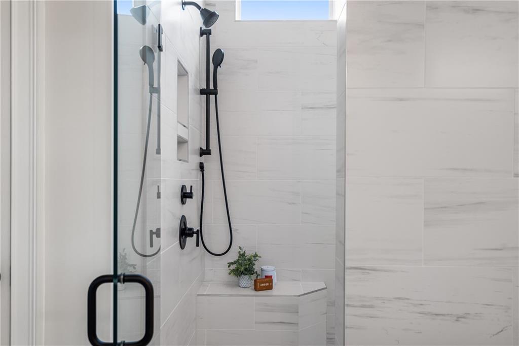 Modern frameless glass shower with rain and handheld heads, white subway tile, niche shelf in Davidson Homes Seaside B master bath, Woodstock GA