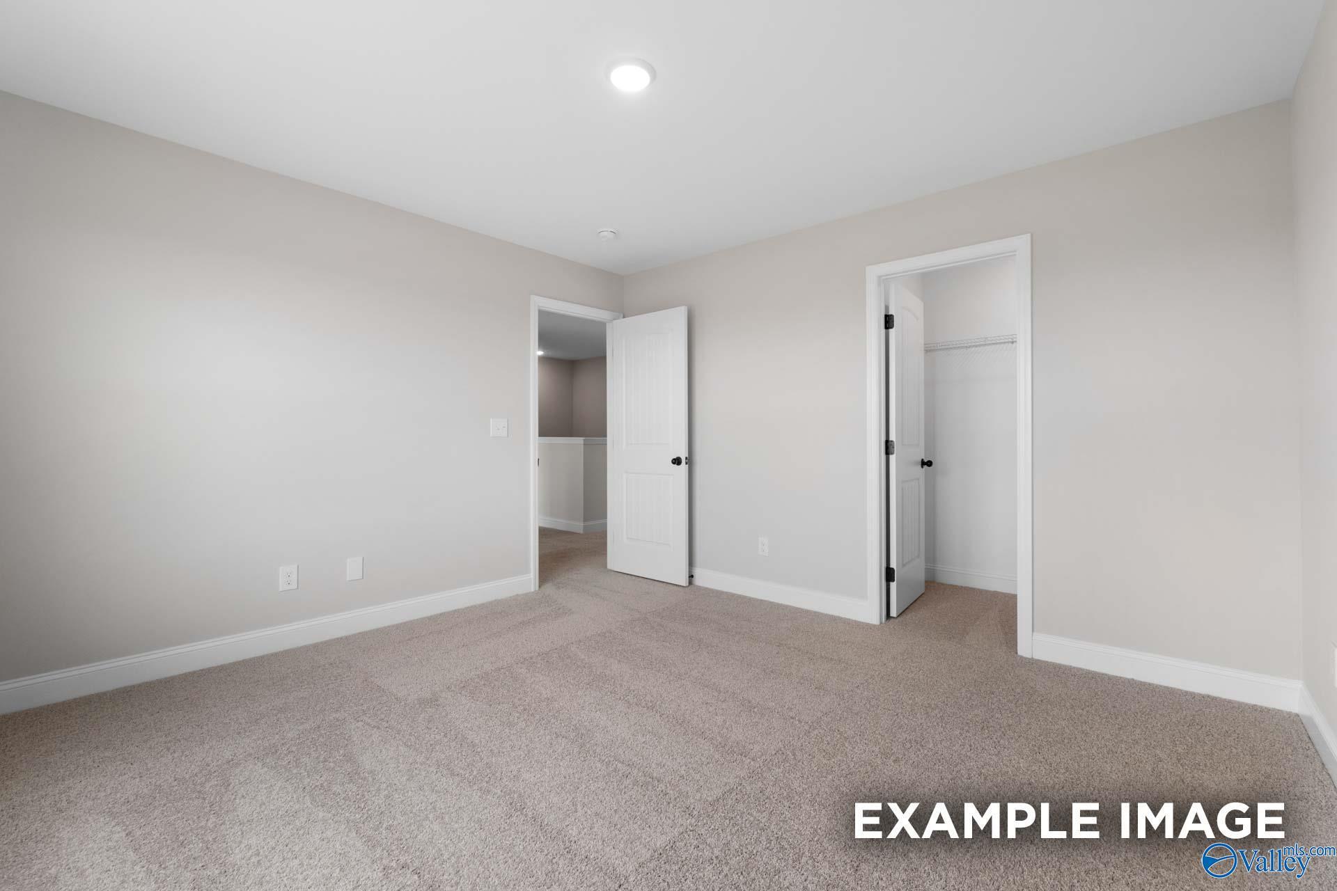Bright, carpeted bedroom with walk-in closet in The Shelby B floor plan at Jaguar Hills, Huntsville, Alabama.