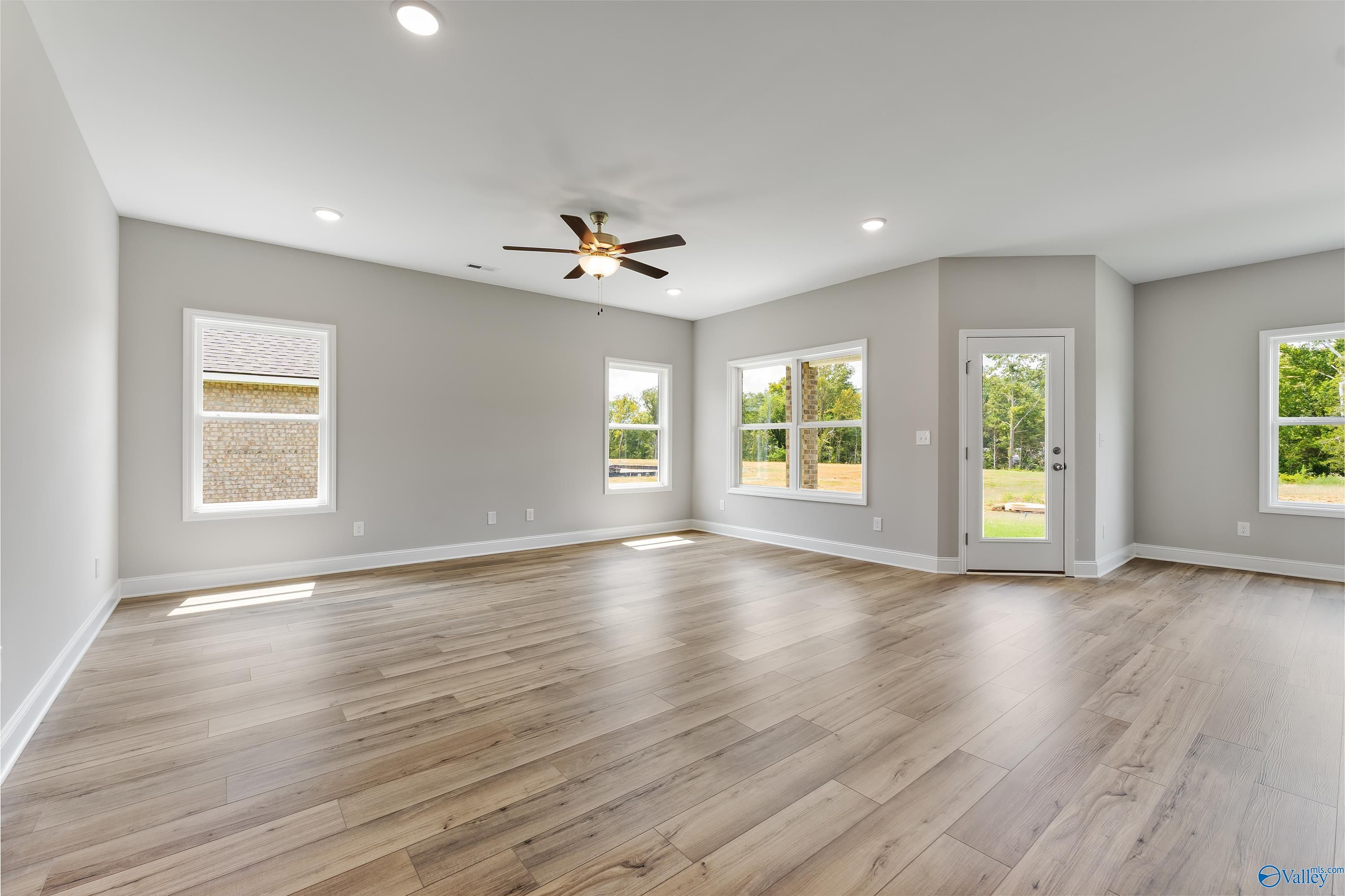 Bright open living room with large windows, ceiling fan, and hardwood floors in Davidson Homes The Franklin C, Huntsville