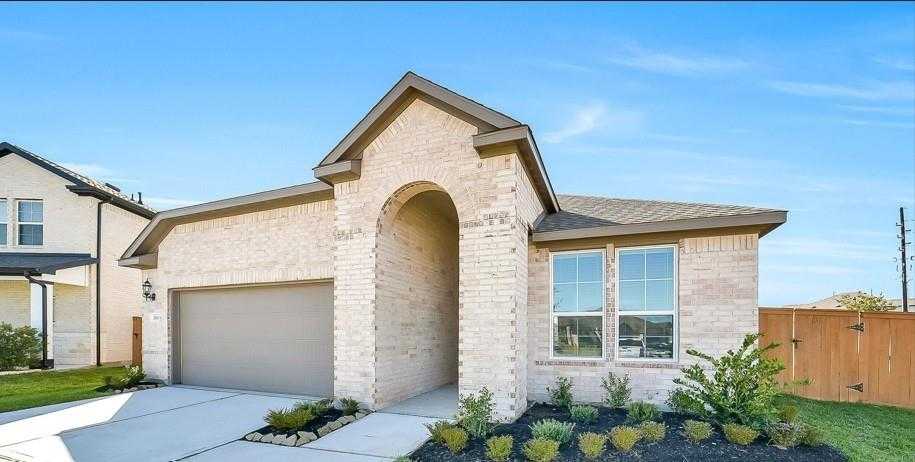 Beige brick single-story home with arched entry, 2-car garage, and landscaped yard in Sunterra, Katy, Texas - Davidson Homes The Acadia A
