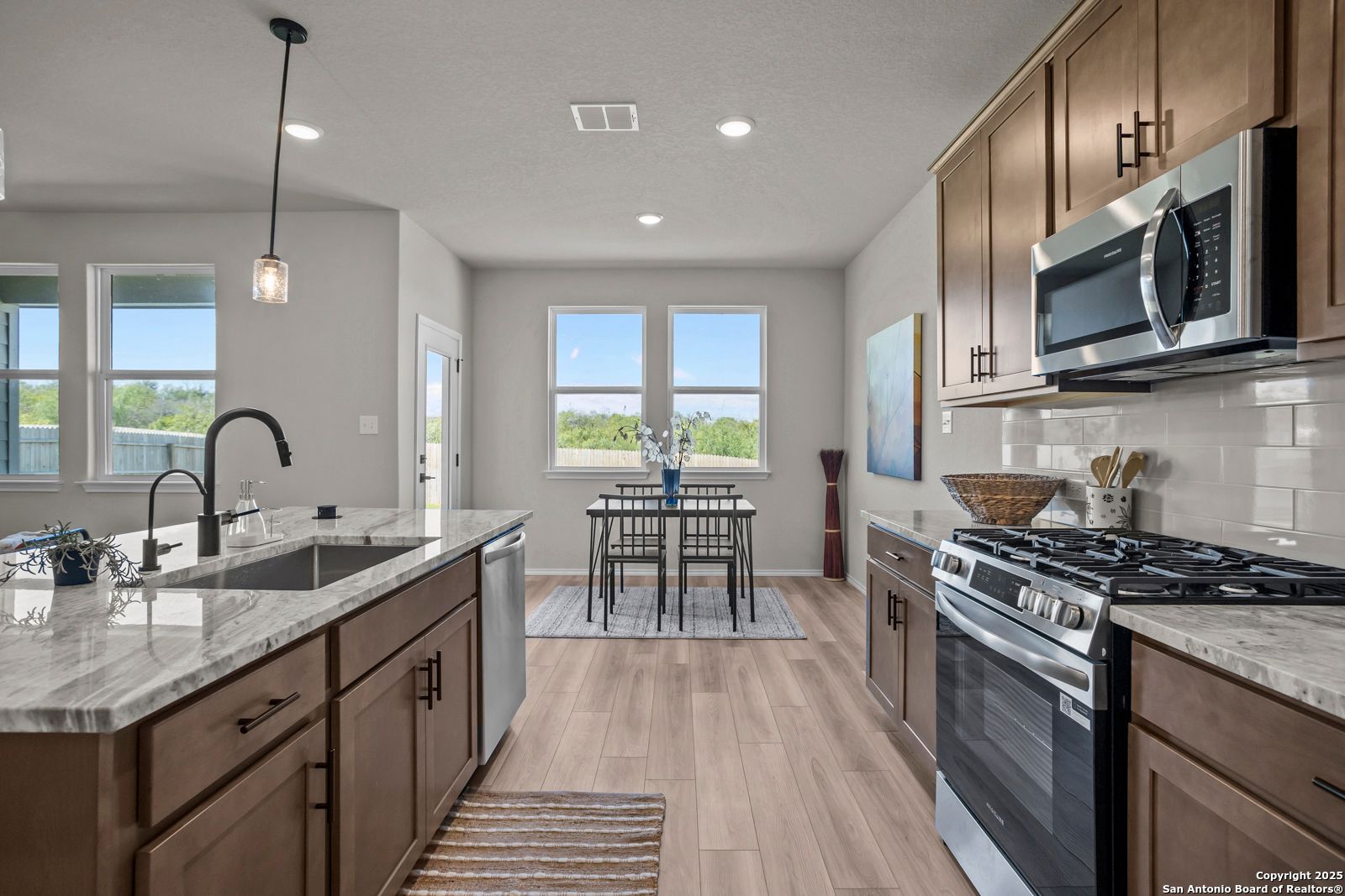 Open-concept kitchen with stainless steel appliances, white quartz countertops, and dining nook in The Asheville H by Davidson Homes, Converse, Texas