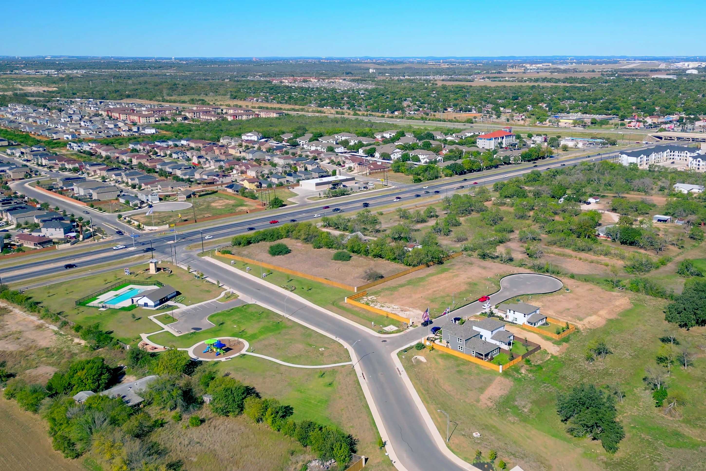 Aerial view of Applewhite Meadows neighborhood in San Antonio TX featuring new homes streets highway and fenced green lots by Davidson Homes
