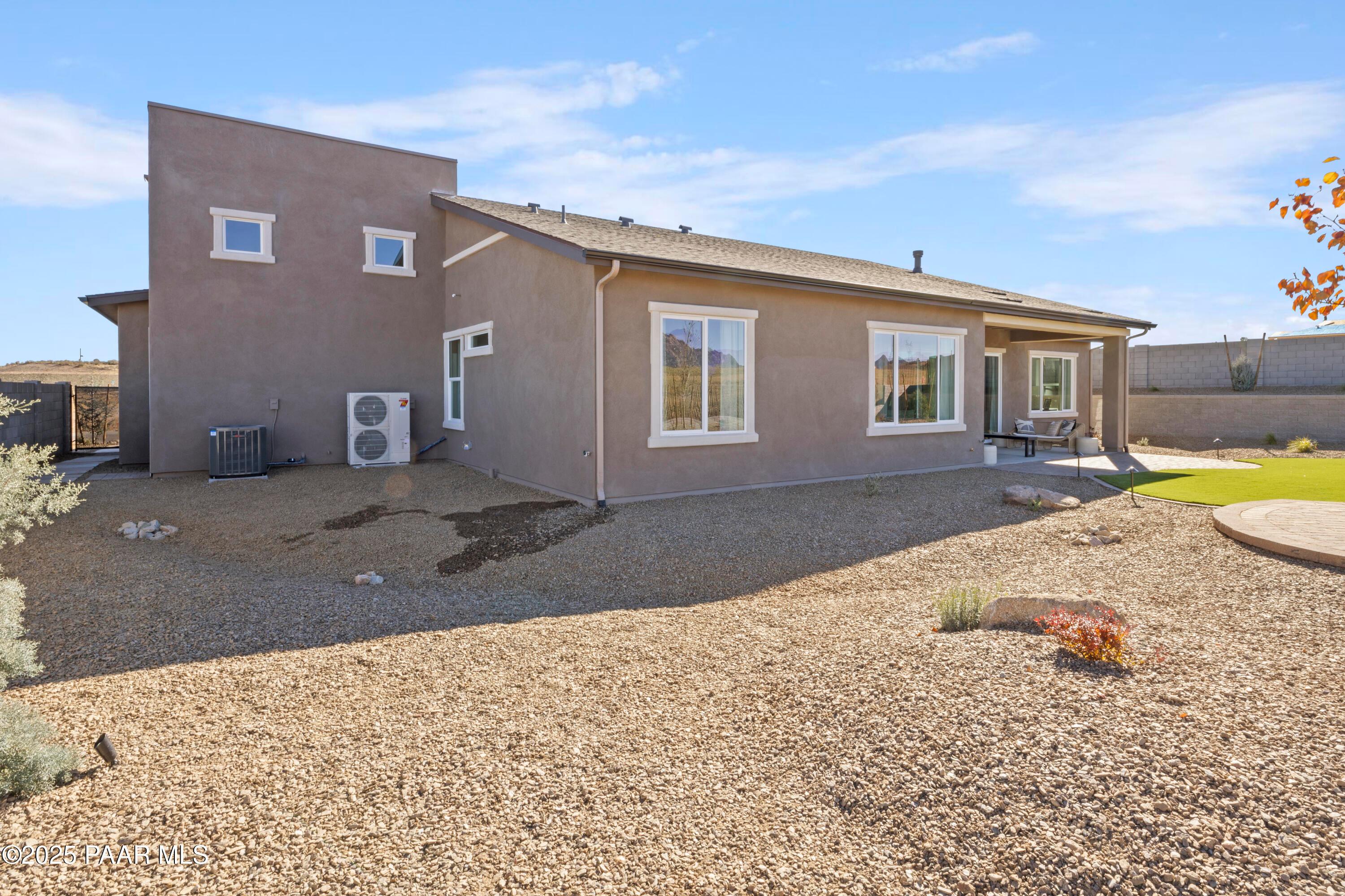 Modern side view of The Blaze D 3-bedroom home by Davidson Homes in Hidden Hills, Prescott, Arizona, featuring large windows, covered patio, and desert gravel landscaping