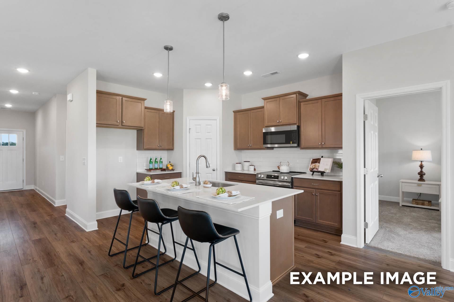 Modern kitchen with island, wood cabinetry, and stainless appliances in The Franklin C floor plan, Heritage Lakes, Alabama.