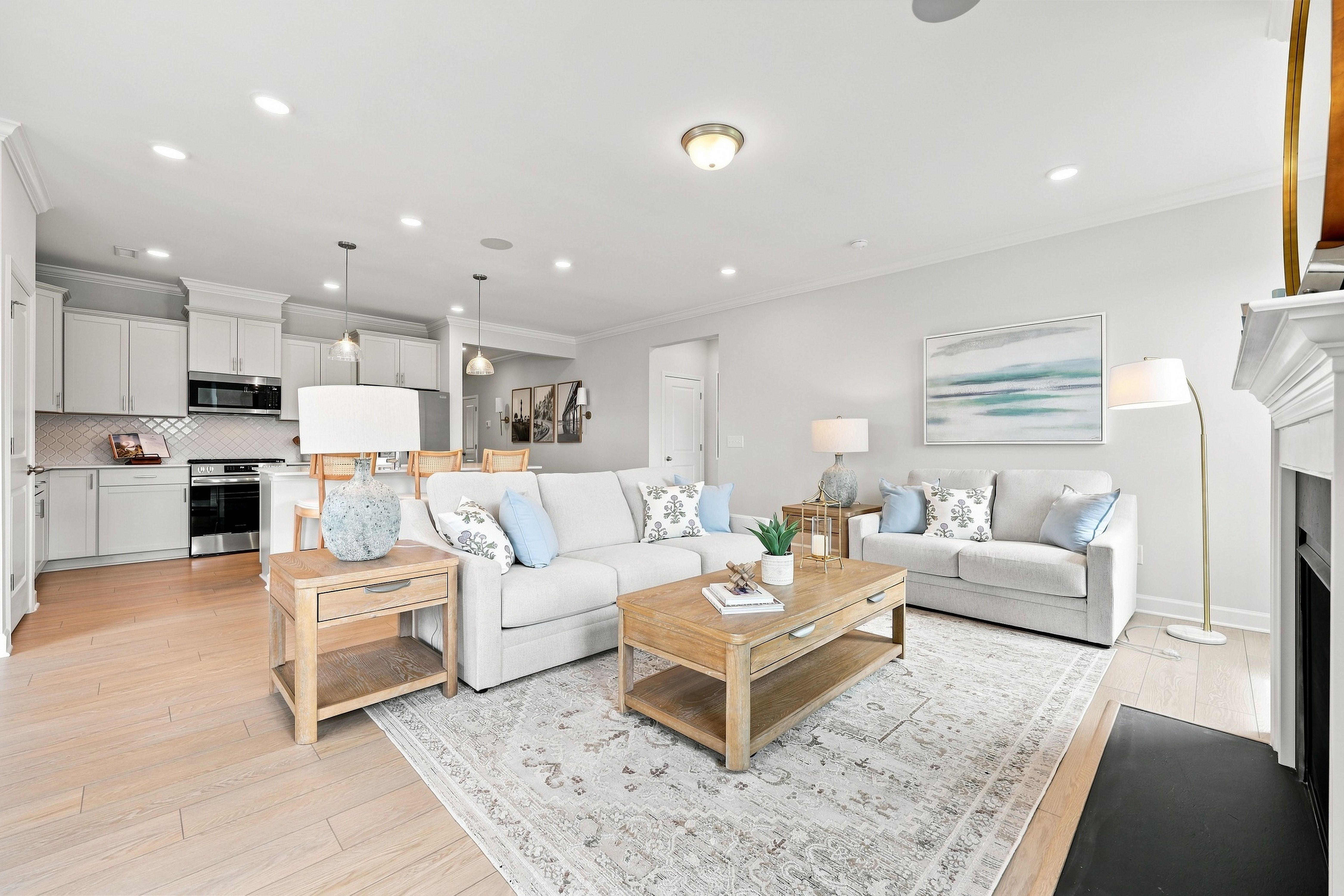 Open-concept living room and kitchen in The Daphne D, featuring modern furniture, a cozy fireplace, and neutral decor.