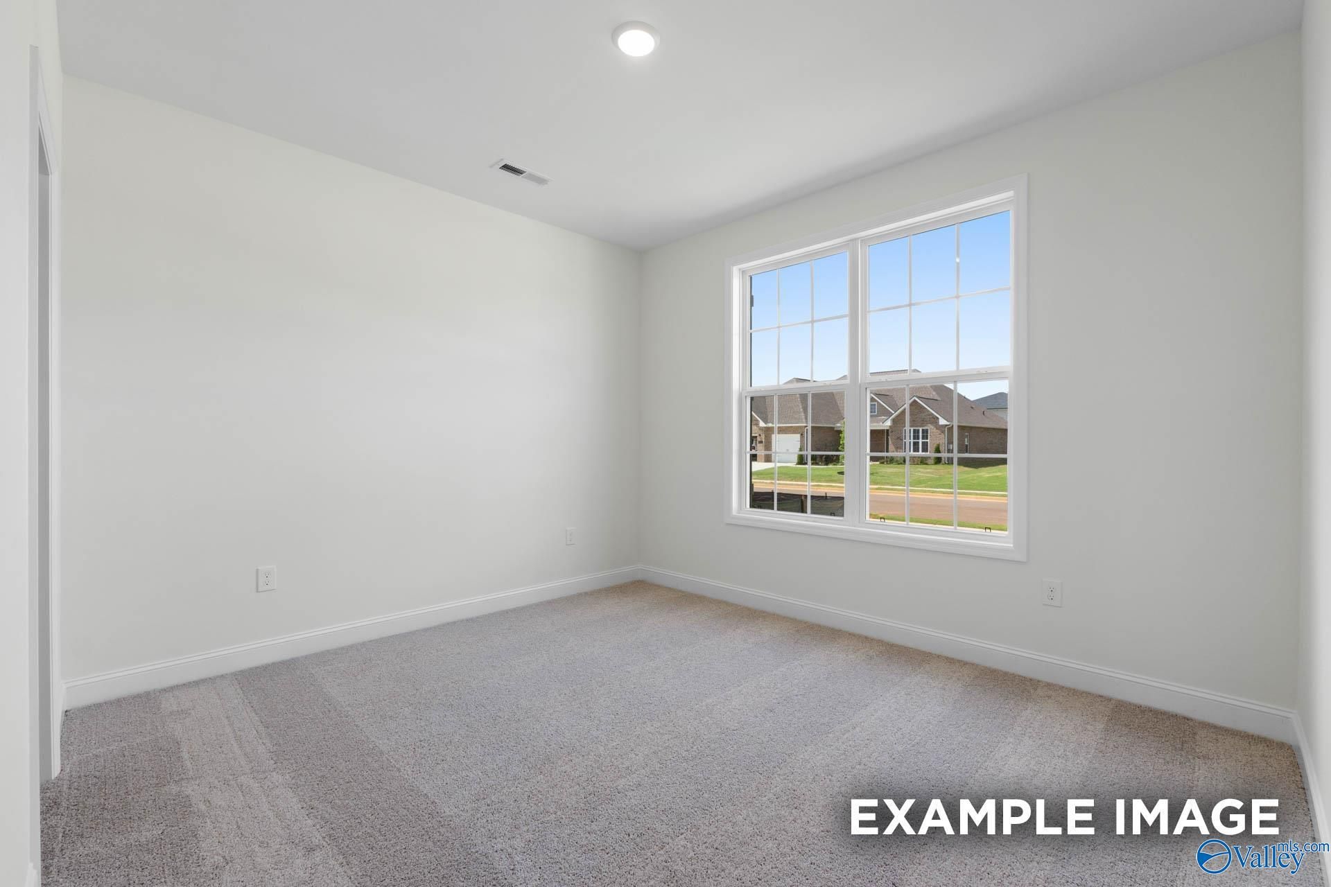 Bright, carpeted bedroom with large window in The Rockford B floor plan at Briercreek in Meridianville, Alabama.