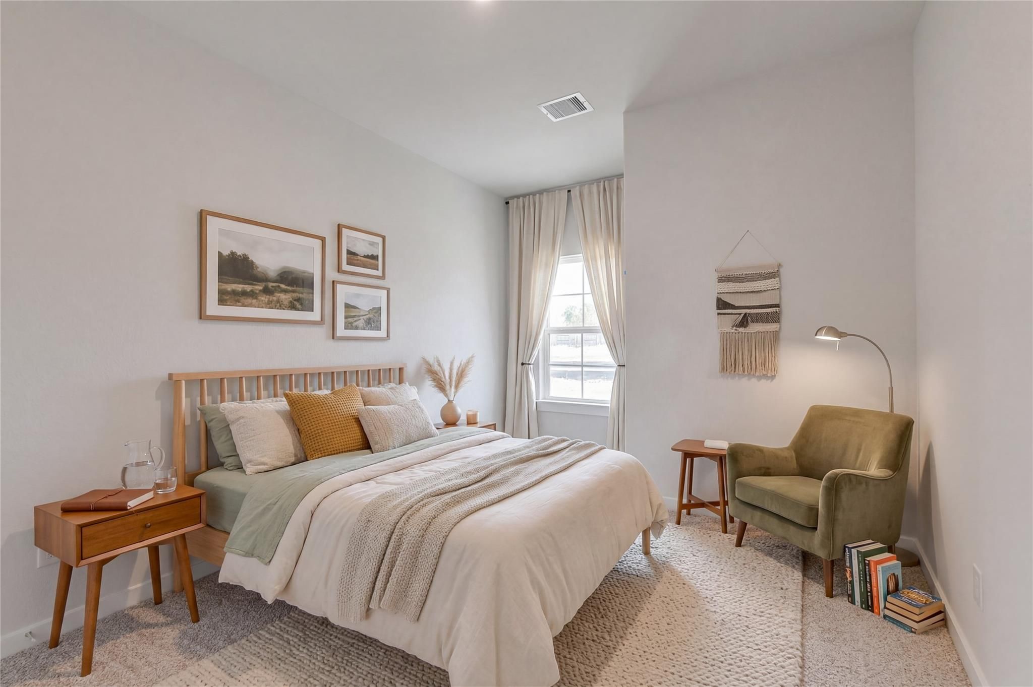 Cozy bedroom with wooden bed frame and sage green accent chair in The Colorado G floor plan at Windmill Estates, Magnolia.