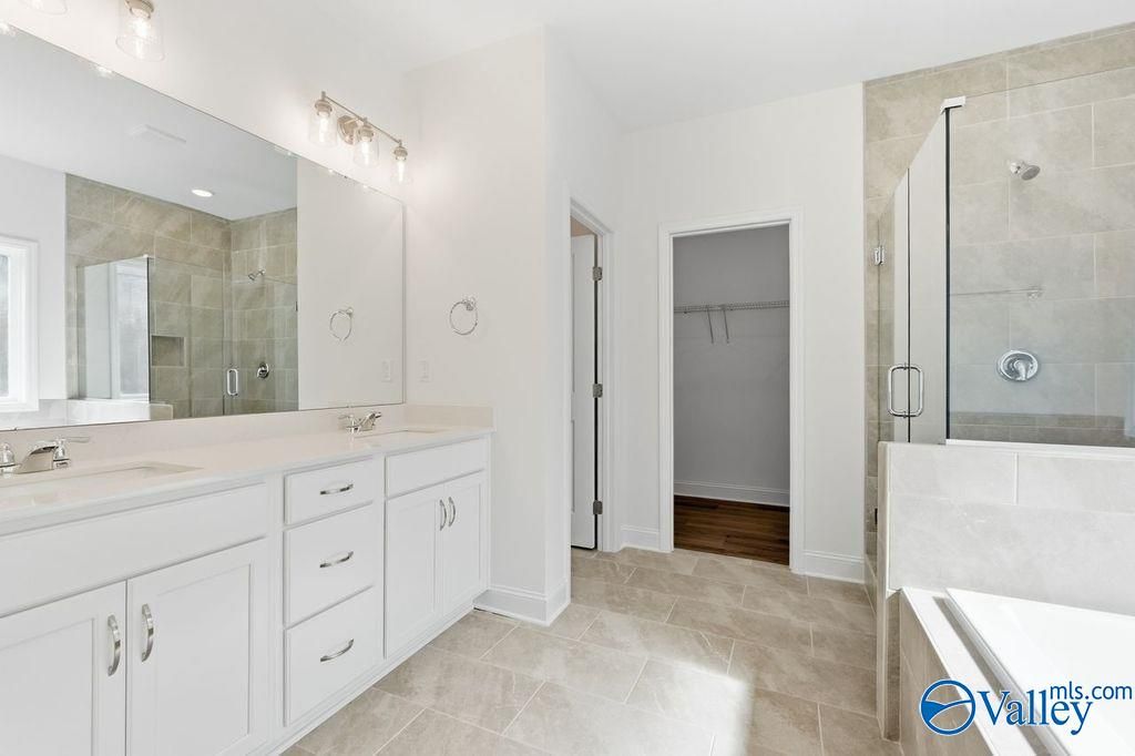 Modern master bathroom with double vanity, frameless glass shower, and walk-in closet in Davidson Homes The Montgomery, Hartselle, Alabama