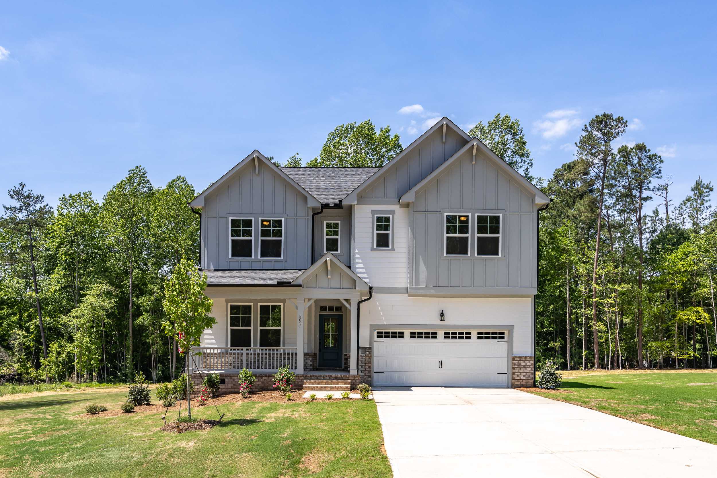 Two-story Beech B home elevation by Davidson Homes in Belmont NC, gray siding, gabled roof, covered porch, 2-car garage, wooded yard