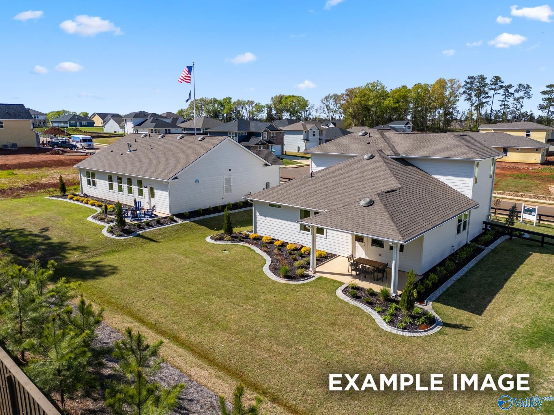 Aerial view of two-story white The Stella home by Davidson Homes in Evergreen Mill, Madison, Alabama, with garage, patio and lush landscaping