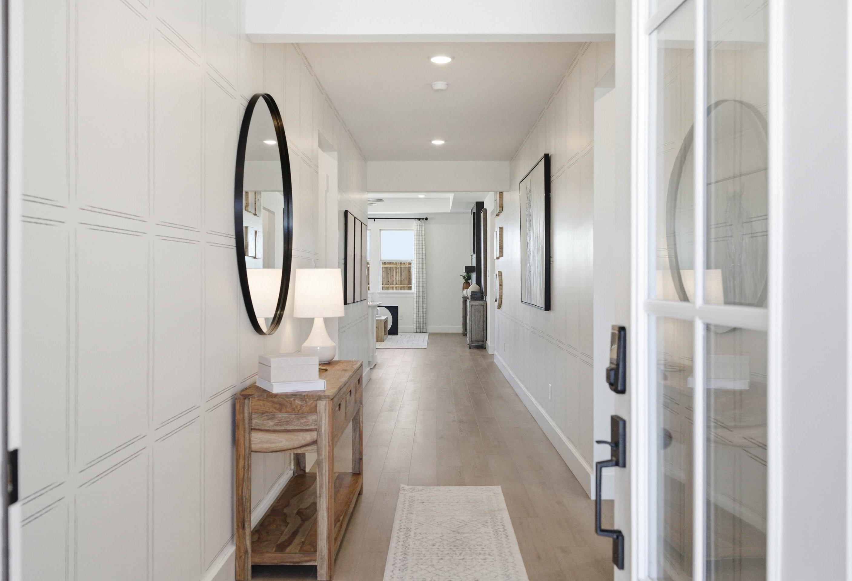 Bright foyer entryway of The Laurel featuring elegant wainscoting, a wood console table, and hardwood flooring.