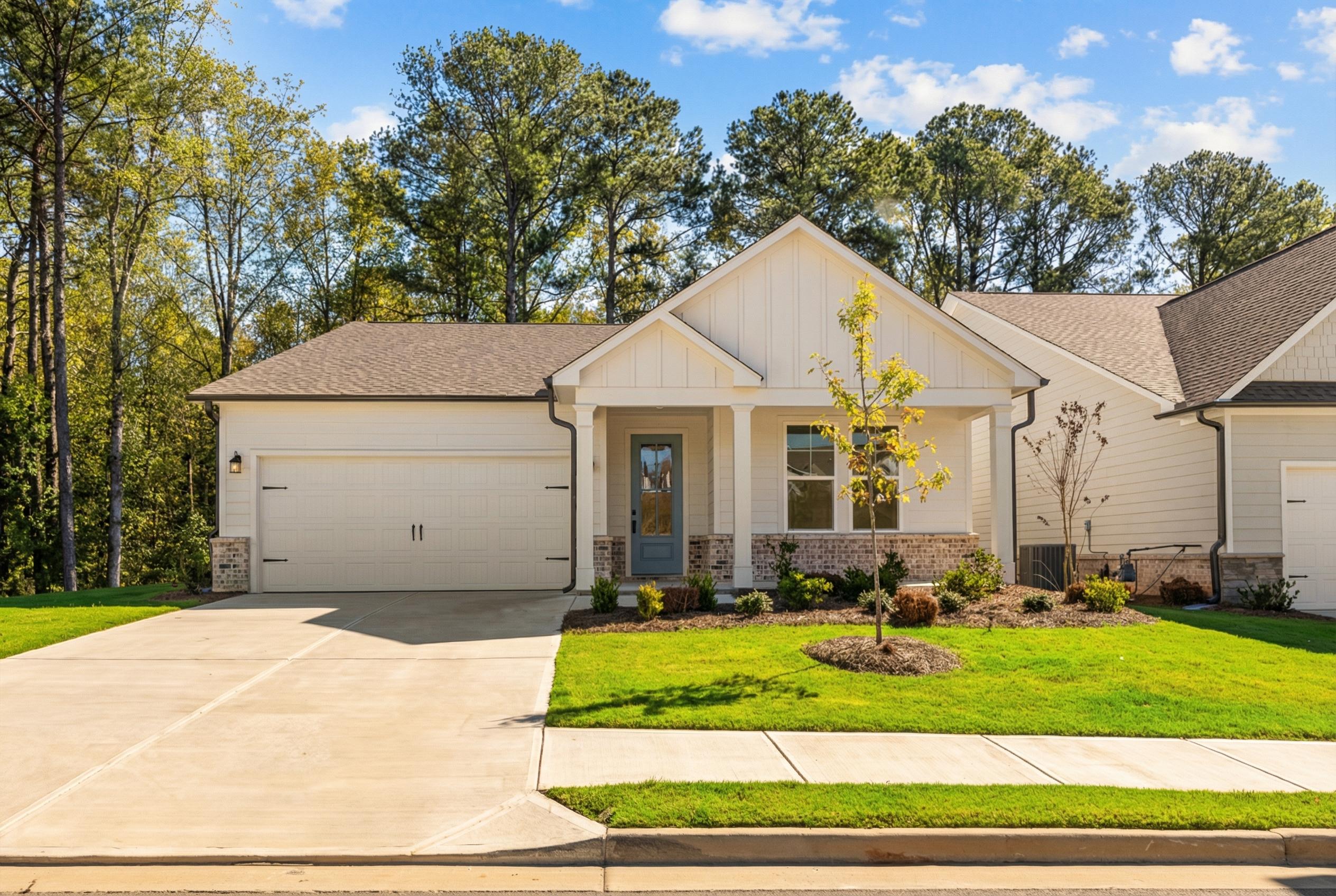 Modern white single-story home with 2-car garage, blue front door, and landscaped yard in Kelly Preserve, Loganville, Georgia