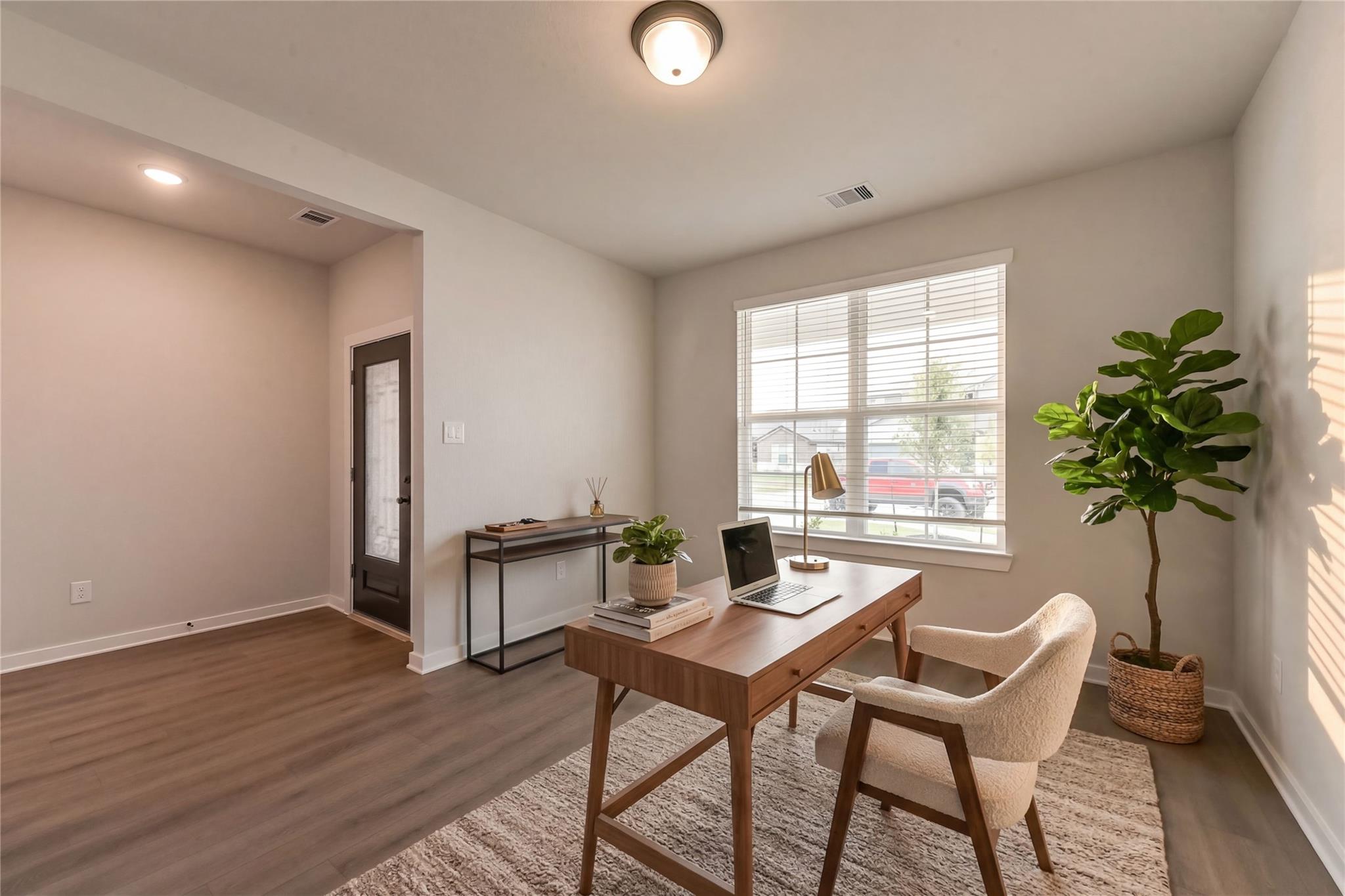 Modern home office with wooden desk, laptop, cream chair, and fiddle leaf fig in Davidson Homes Everett C, Crosby, Texas