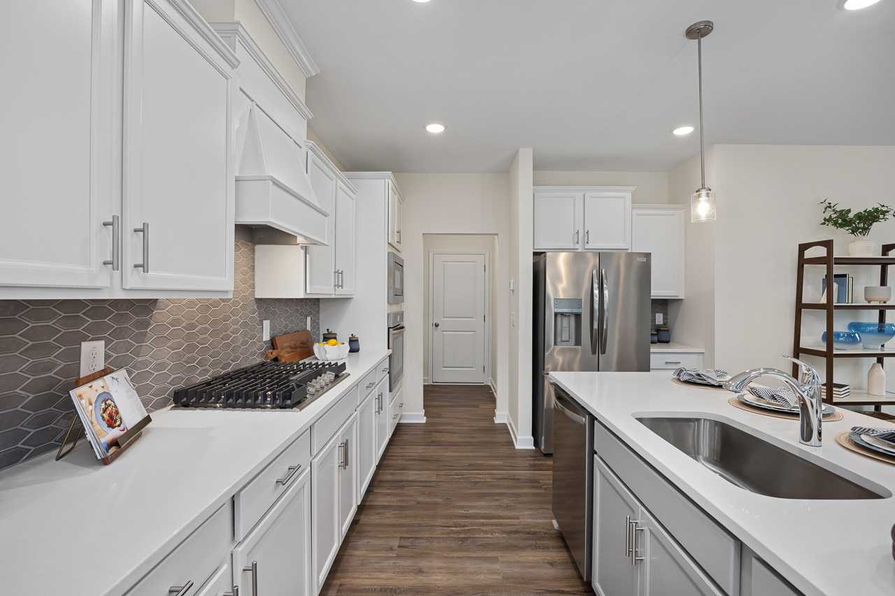 Spacious white kitchen in Gregory Village Townhomes Lillington NC featuring shaker cabinets, stainless steel appliances, quartz counters, subway tile backsplash, hardwood floors