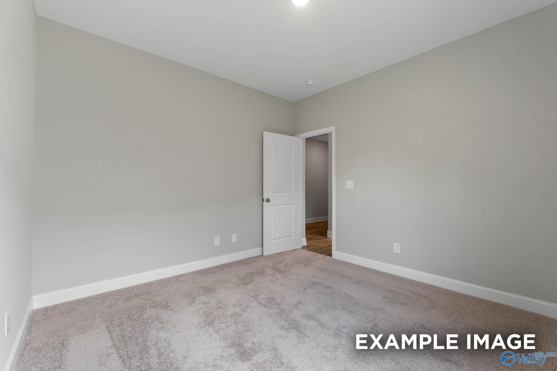 Bright secondary bedroom with neutral gray walls, open white door, and beige carpet in Davidson Homes Everett B, Athens, Alabama