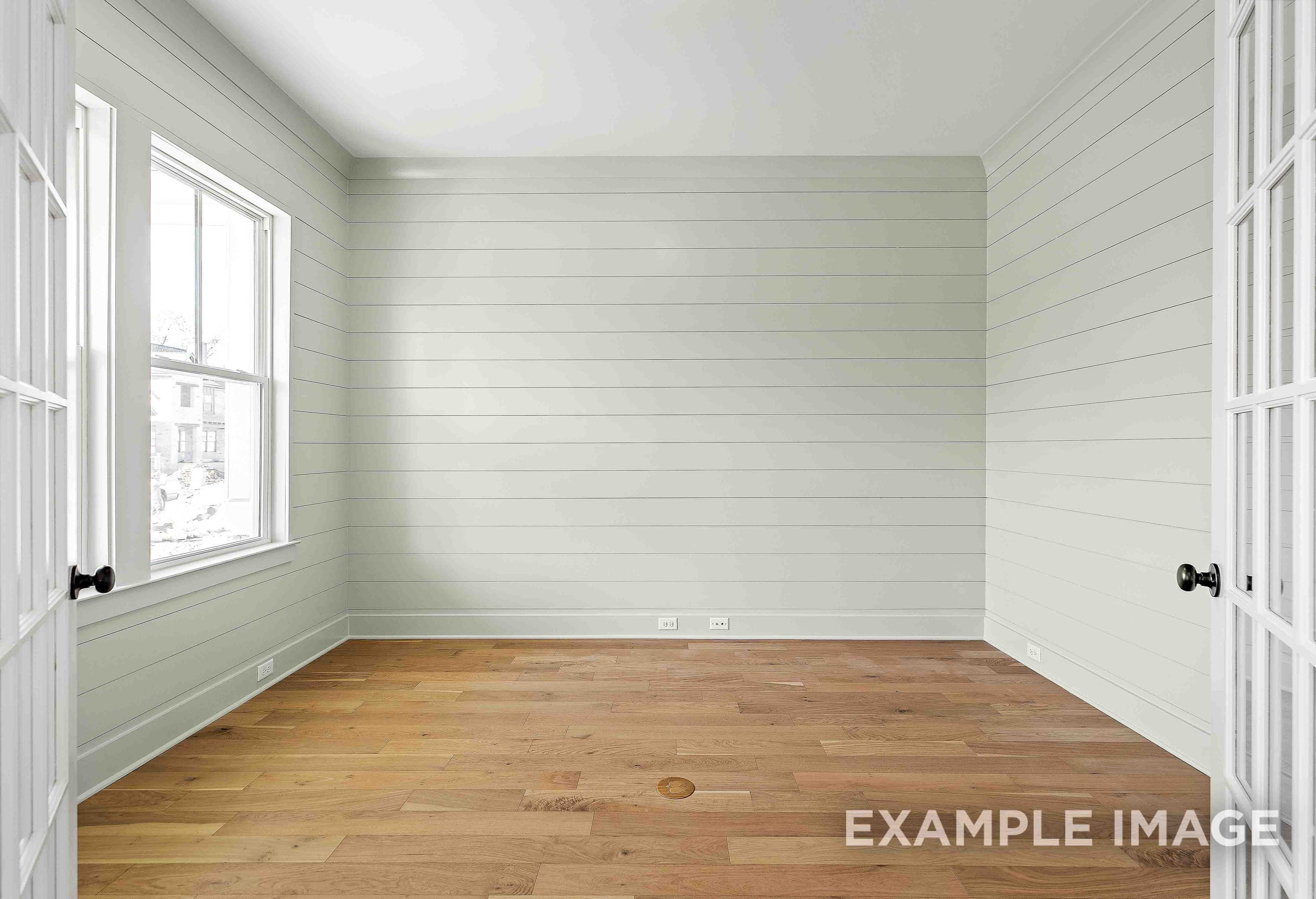 Bright empty bedroom in The Albany A featuring light shiplap walls, large windows, and warm oak hardwood floors