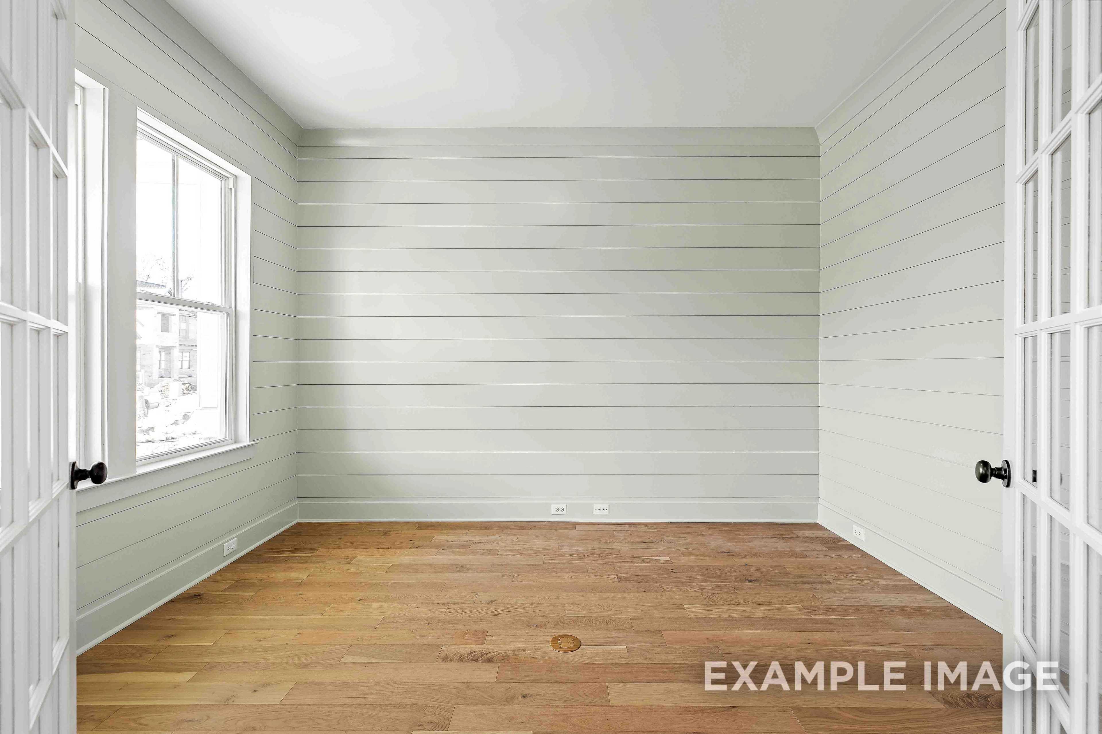 Bright empty bedroom in The Albany A featuring light shiplap walls, large windows, and warm oak hardwood floors