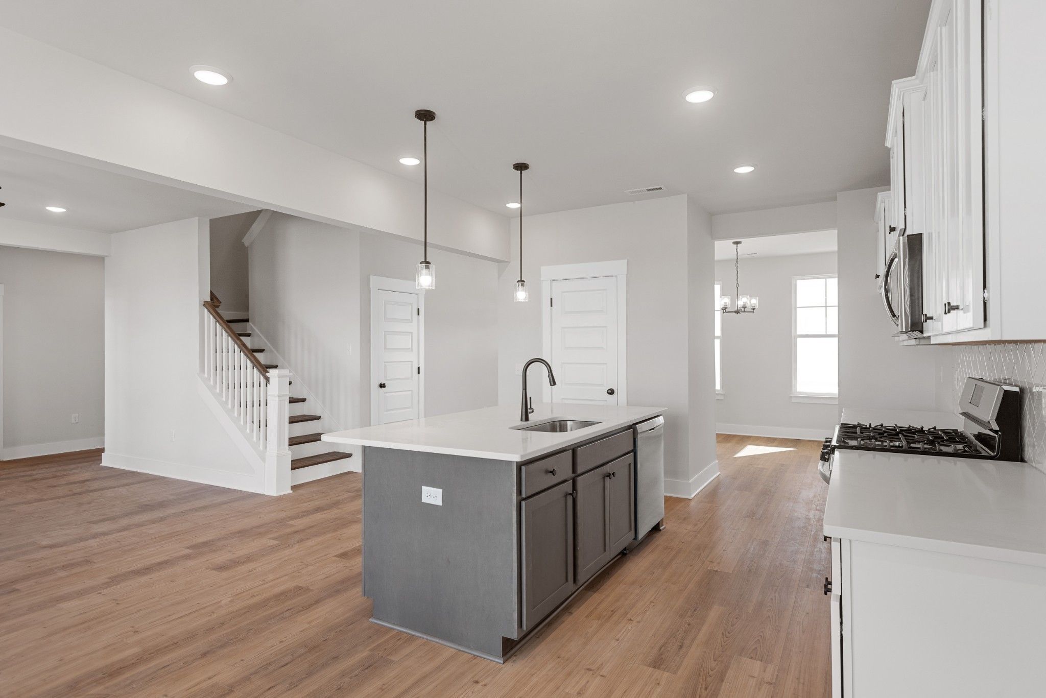 Modern kitchen with gray island and white cabinets in The Willow B floor plan at Calista Farms in White House, Tennessee.