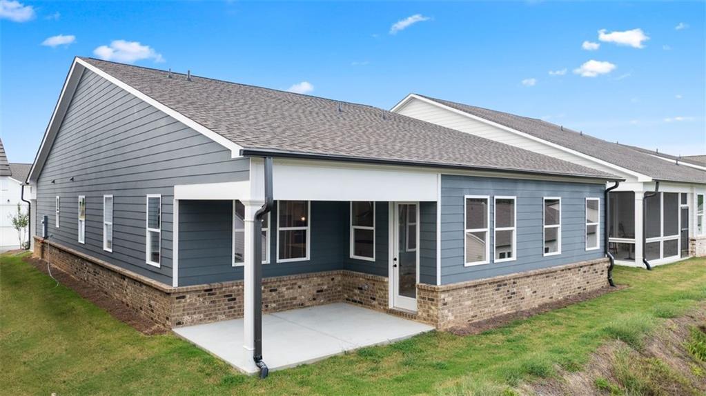 Gray single-story home exterior with covered screened patio, windows, and brick base in Kelly Preserve, Loganville, Georgia