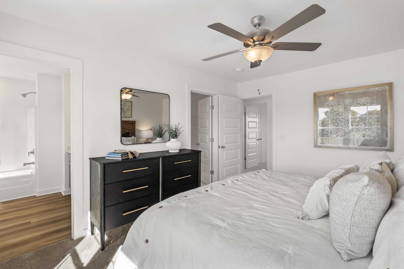 Elegant master bedroom with king bed, black dresser, ceiling fan, and en-suite bath in Davidson Homes The Cumberland B, Gallatin, TN