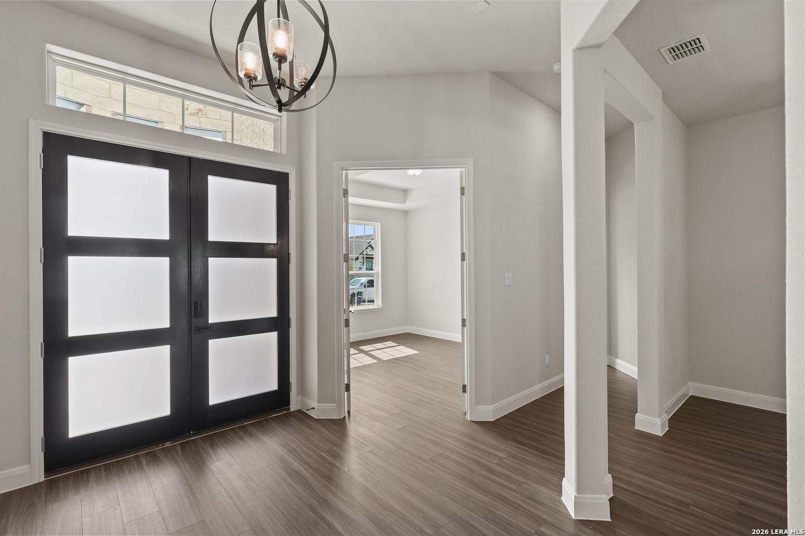 Modern entryway with black double doors and chandelier in The Summerlin B floor plan at Potranco Oaks, Castroville, Texas.