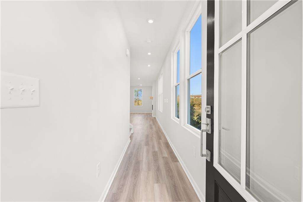 Bright hallway with white walls, laminate flooring, recessed lights, and large windows in Davidson Homes The Cary A, Winder, Georgia