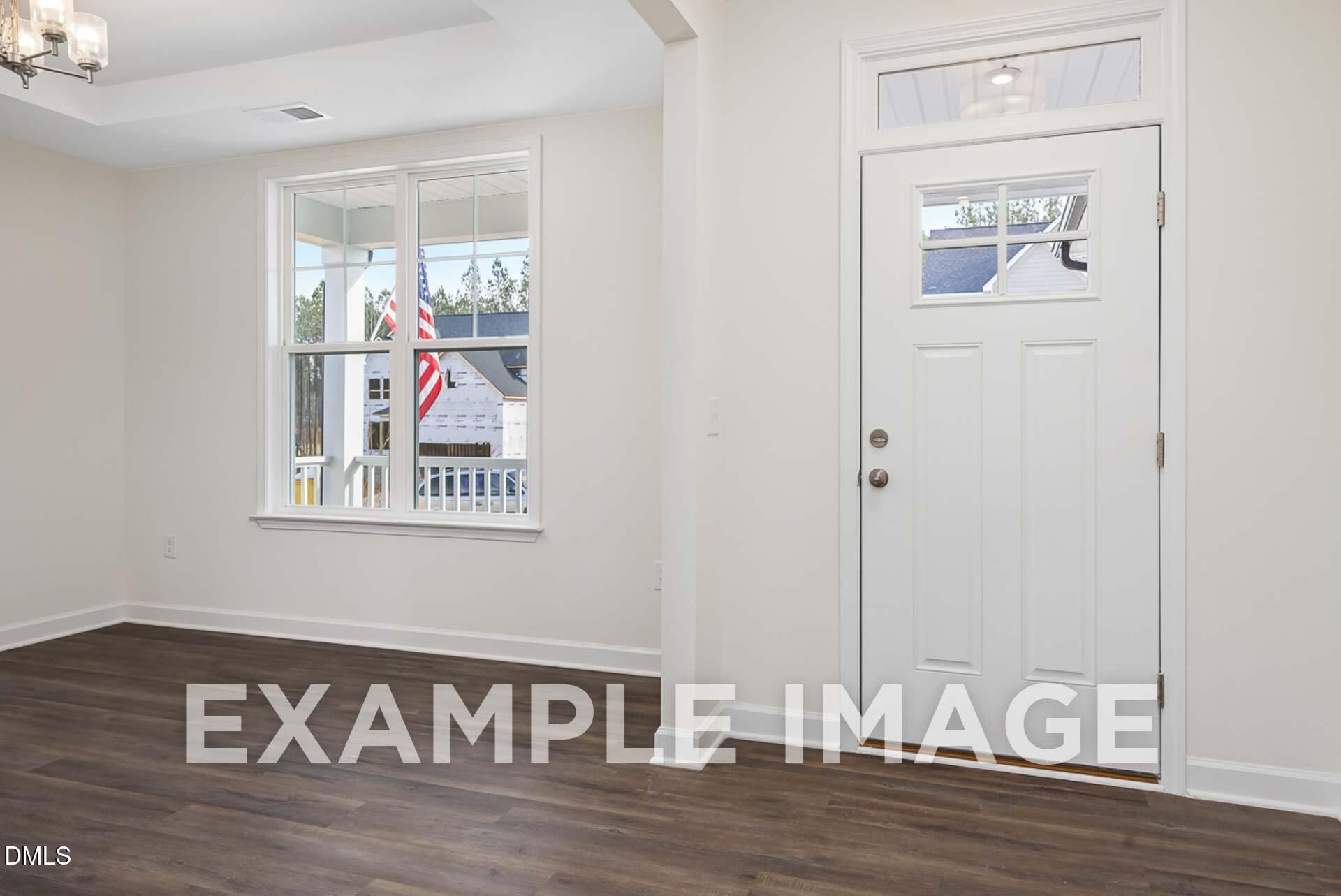 Bright entryway with hardwood floors, transom window, and white front door in Davidson Homes The Ash B, Zebulon, NC