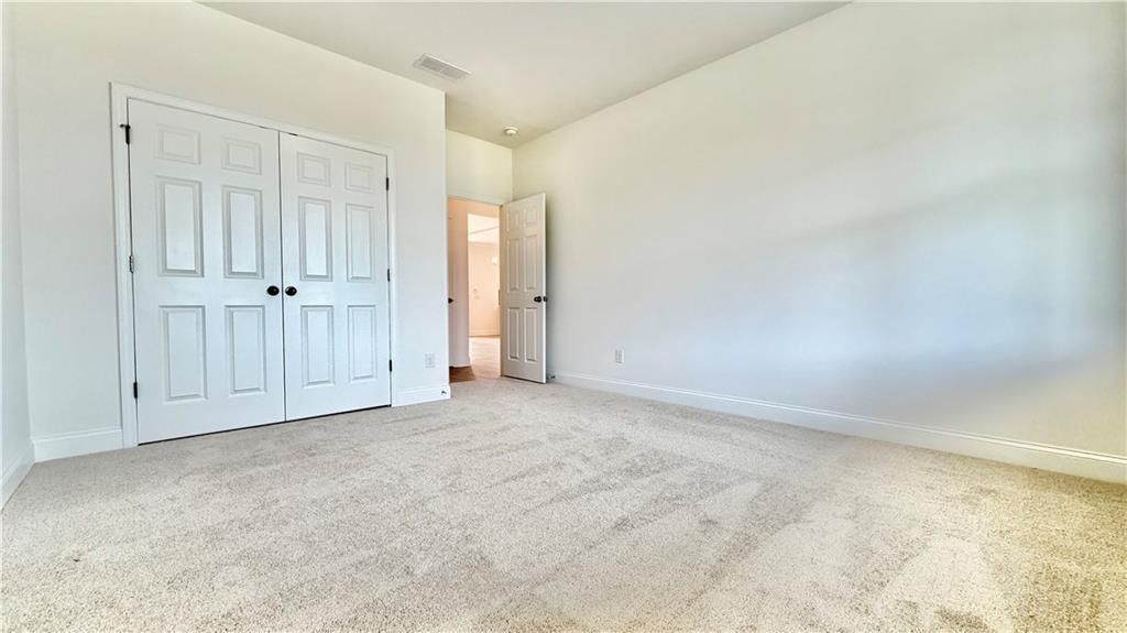 Spacious secondary bedroom with neutral carpet and double-door closet in The Hickory C floor plan, Wehunt Meadows.