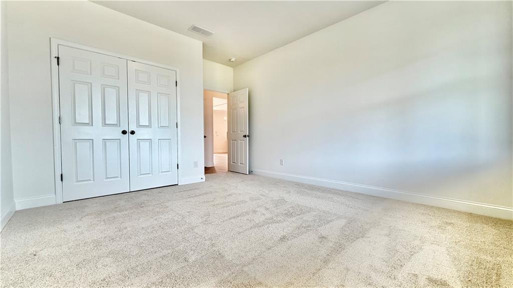 Spacious secondary bedroom with neutral carpet and double-door closet in The Hickory C floor plan, Wehunt Meadows.